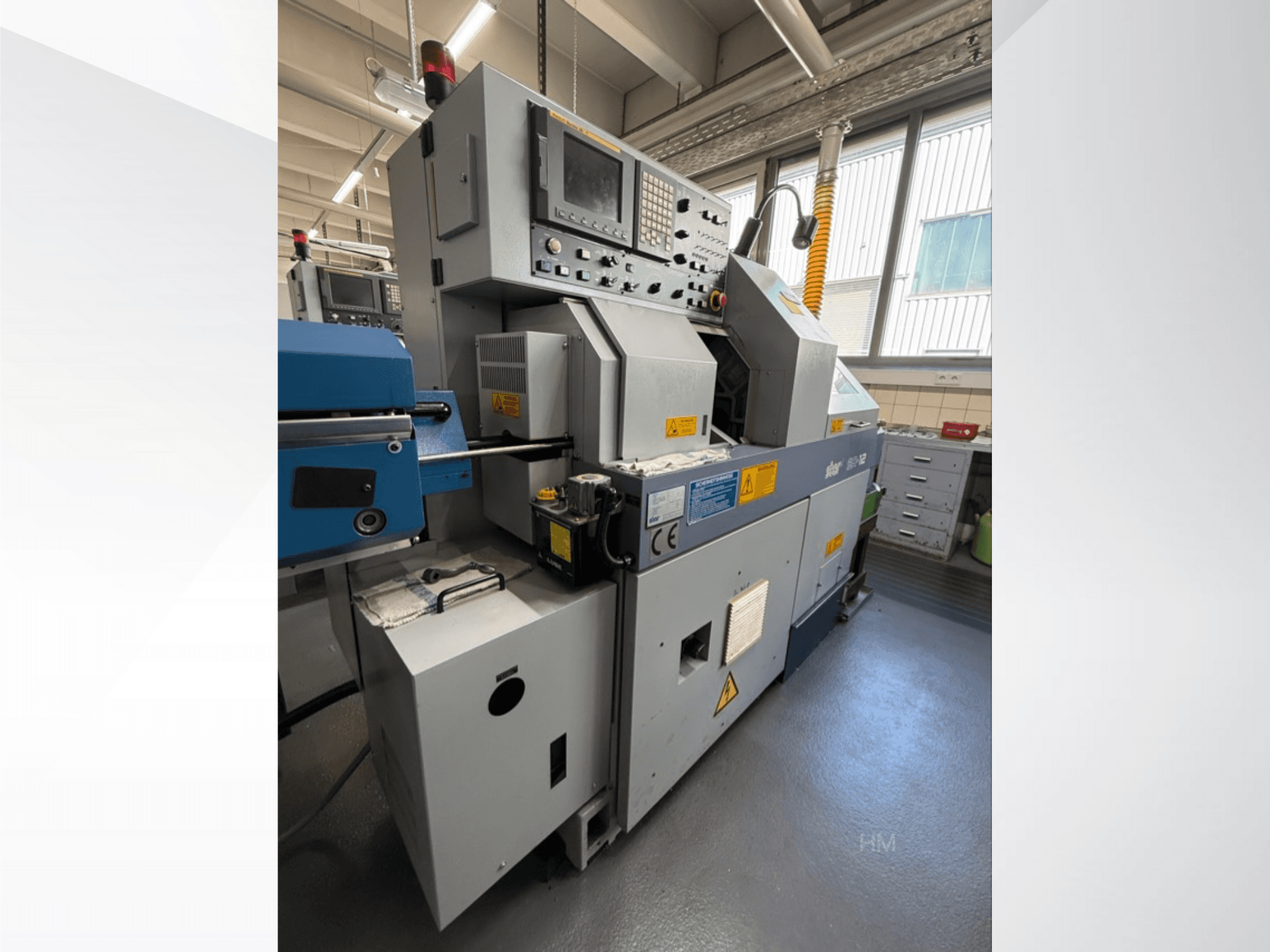 Lithec 3231 masina esikülg, kus on näidatud juhtpaneel, mootor ja sinine söötmisosa hästi valgustatud tööstuslikus keskkonnas.