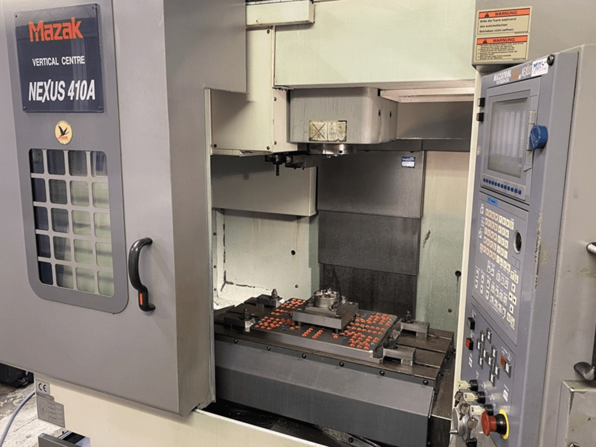 Mazak VCN410 vertikaalne töötluskeskus, esiplaanil on näidatud juhtpaneel ja masina sisemus koos paigaldatud töödeldava detailiga.