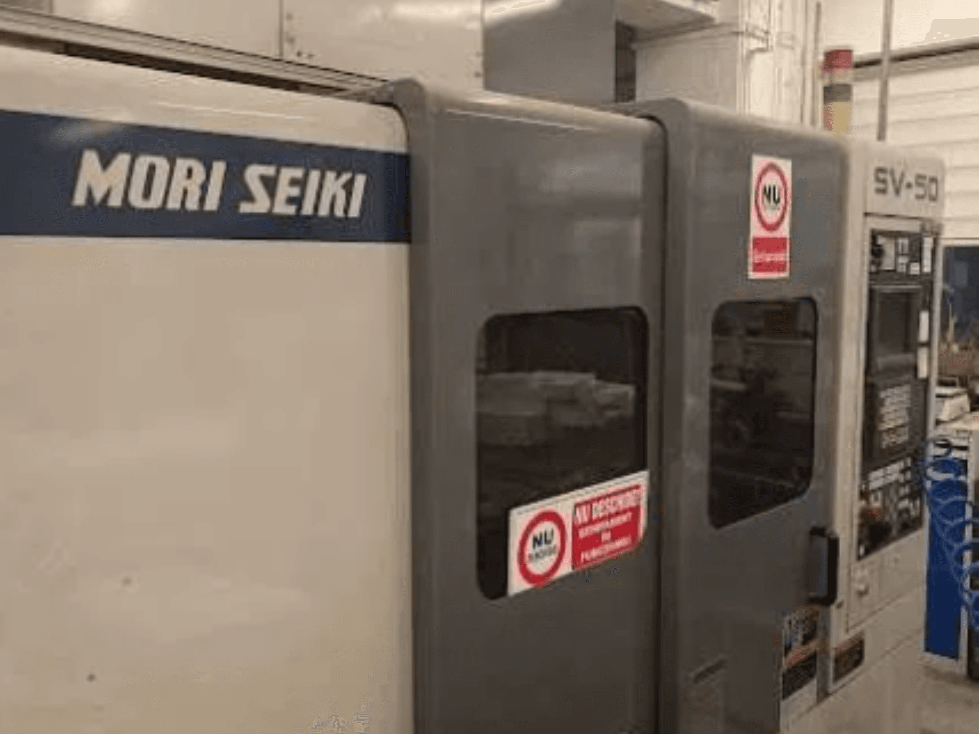 MORI SEIKI SV-50 CNC-tööpink, külgvaade; juhtpaneel ja ohutushoiatuskleebised.