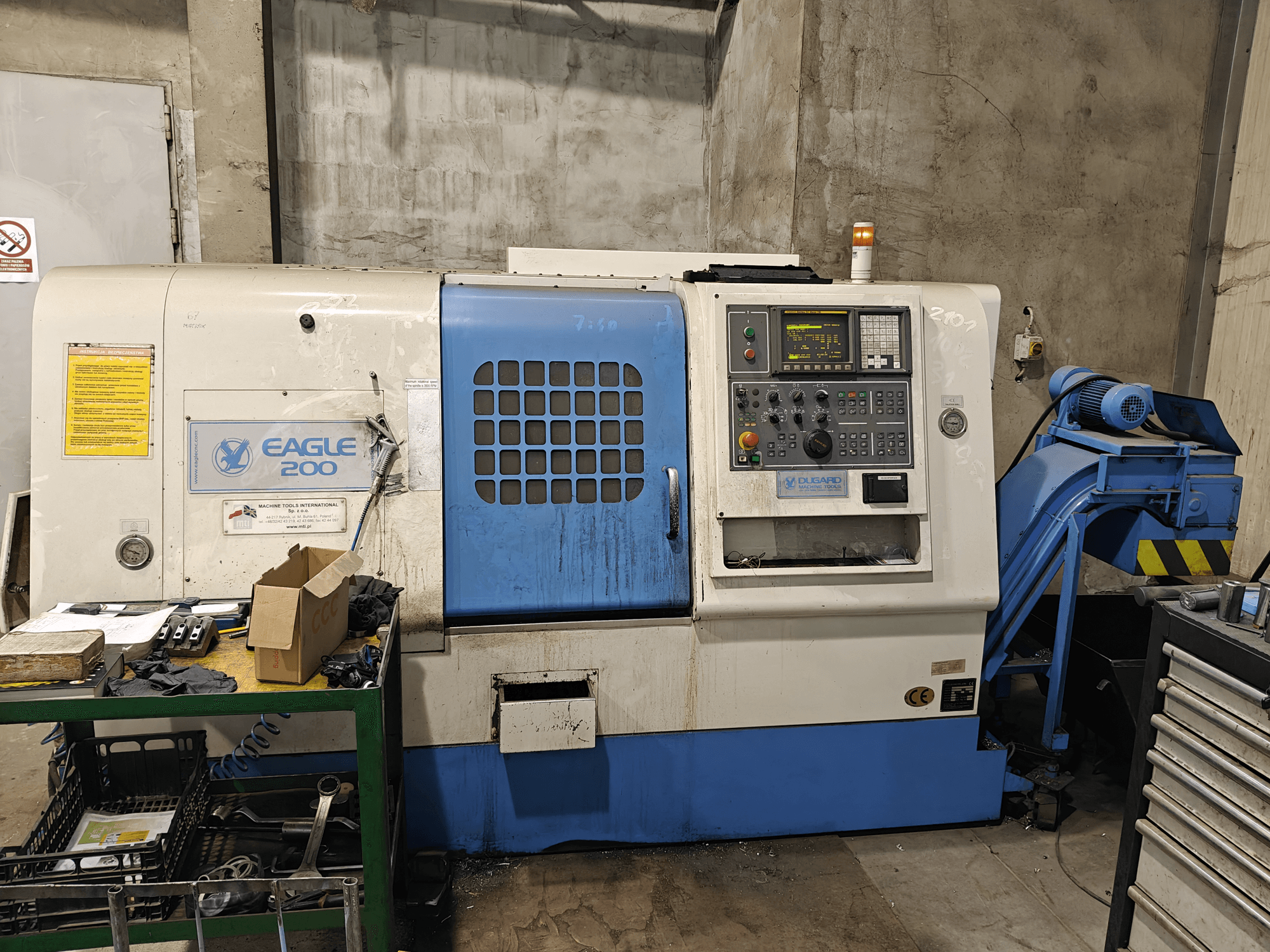 Eagle 200 CNC-tööpink, esivaade juhtpaneeliga, erinevad tööriistad rohelisel kärul. Nähtav kulumine ja töökorras tuled.