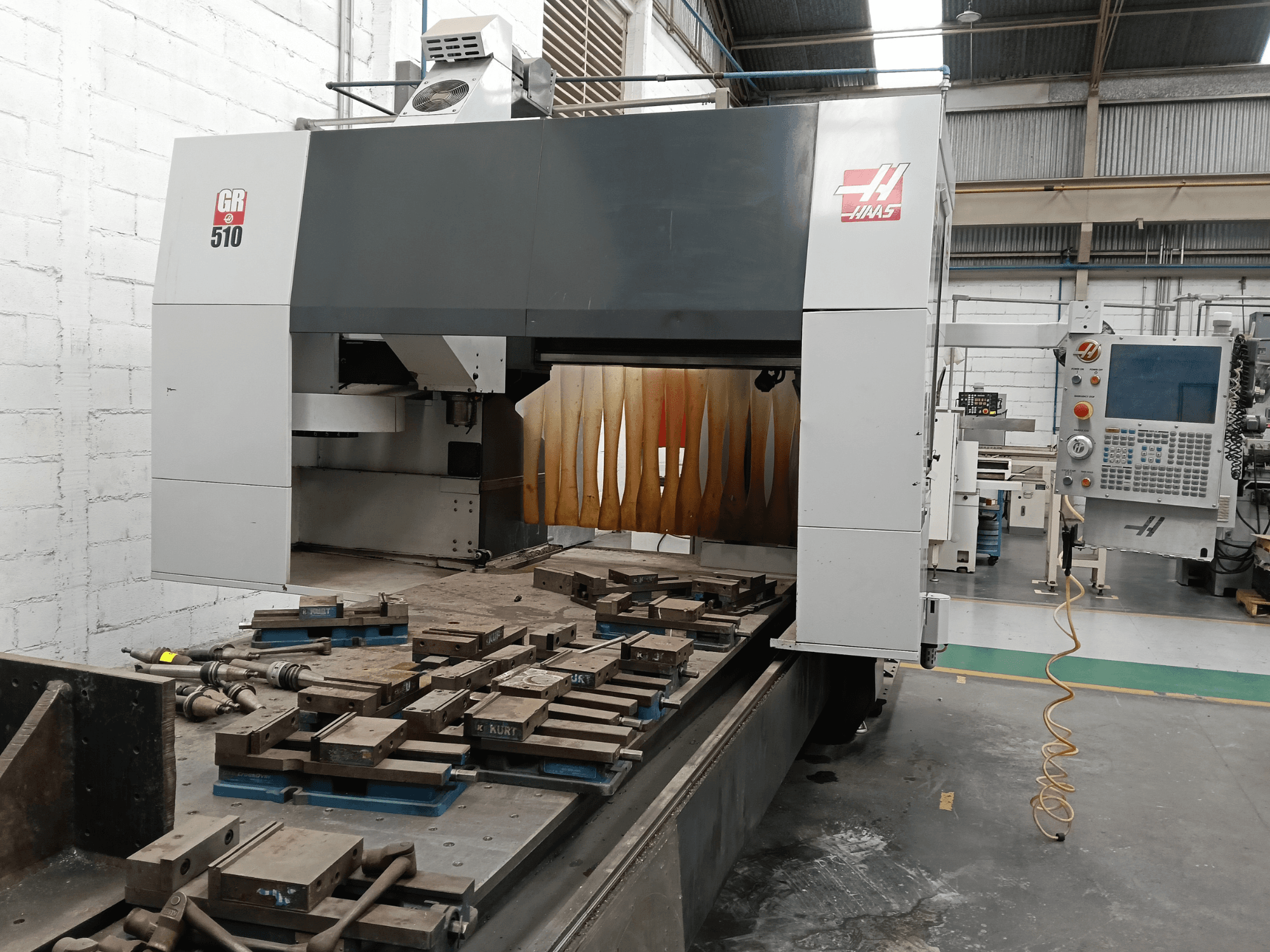 HAAS GR-510 portaalfreesmasina vaade eest, millel on näha juhtpaneel ja töötlemislaual olevad töödeldud detailid.