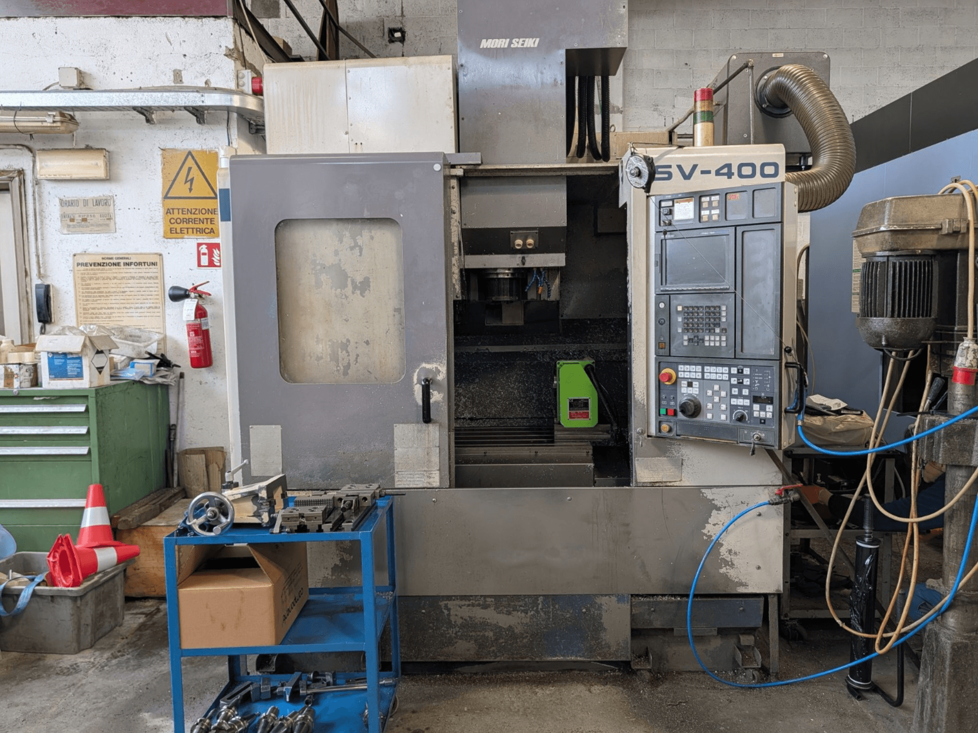 MORI SEIKI SV-400 vertikaalne töötluskeskus töökojas, külgvaade, kus näidatakse juhtpaneeli ja tööpinkide lähedal.