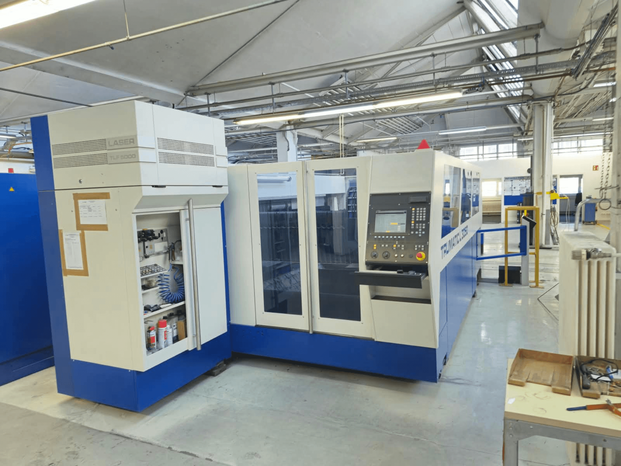 TRUMPF TruLaser L3050 CO₂-laserlõikepink, vaade eest, millel on juhtpaneel ja hooldusluuk, tehase seadistuses.