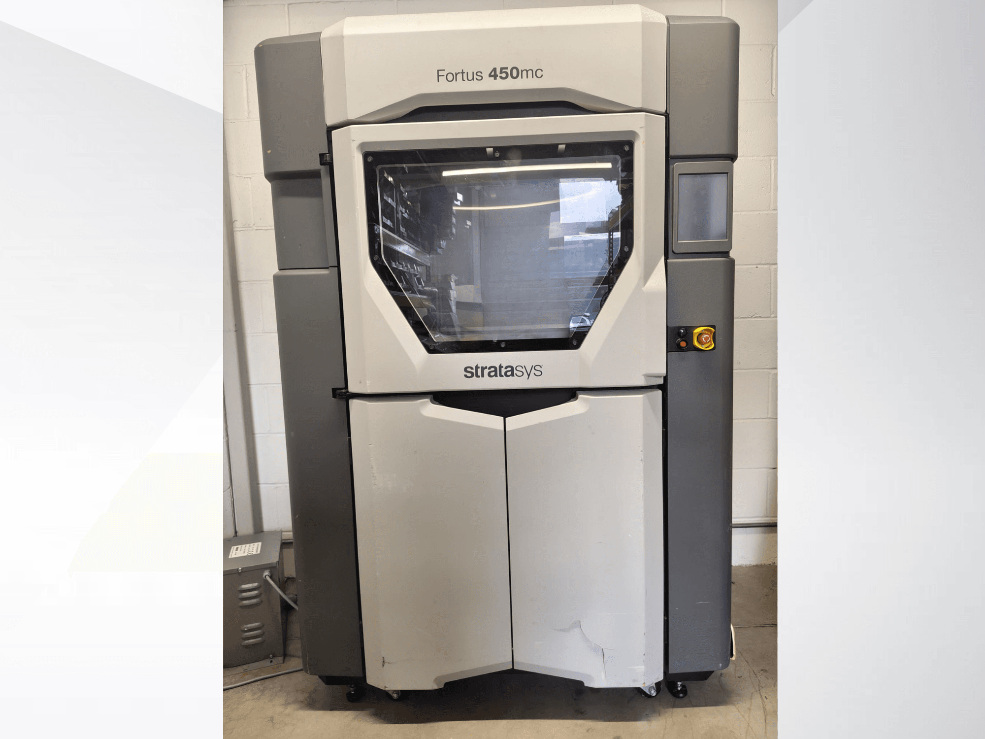Stratasys Fortus 450mc plastitöötlemisseade, vaade eest, millel on suur aken, juhtpaneel ja tööstuslik disain.