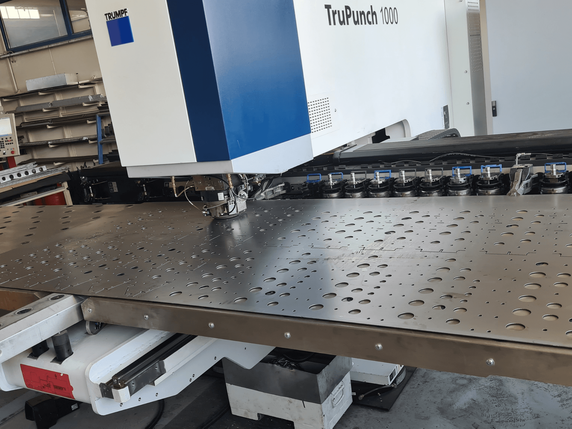CNC-stantsimismasin TRUMPF TruPunch 1000, vaade eest, millel on näha perforeeritud metallplaat ja tööriistade paigutus.