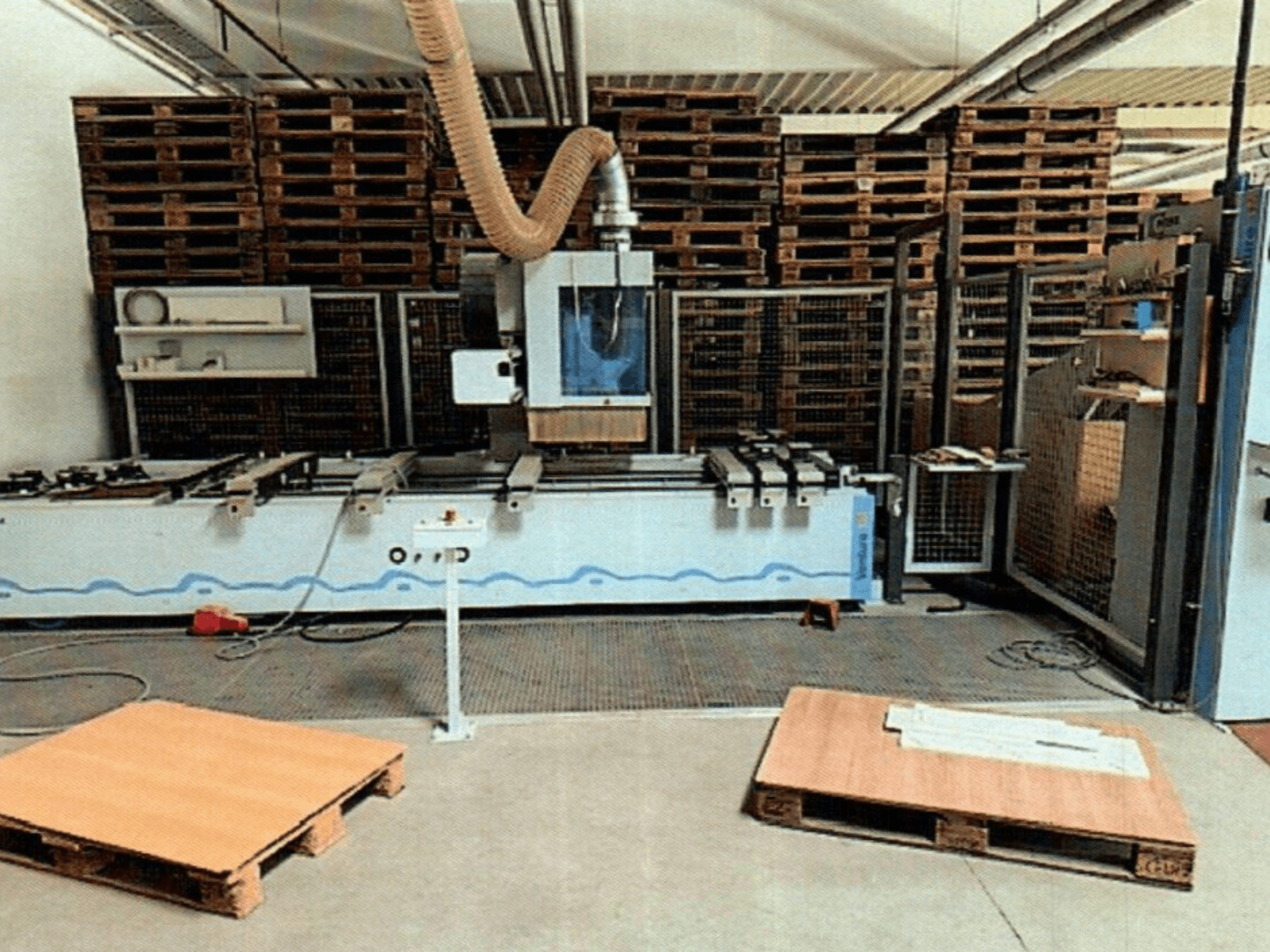 CNC-puidutöötluskeskus Weeke Venture 1M töökojas, esiplaanil puidust kaubaalused ja tööstuslik seadistus.