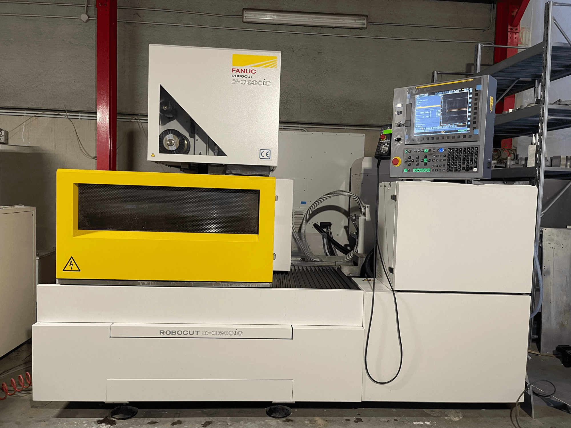FANUC Robocut α-C600iC, kollase kaitsekatte ja juhtpaneeliga CNC-pingi külgvaade, mis näitab täpset lõikamisvõimet.