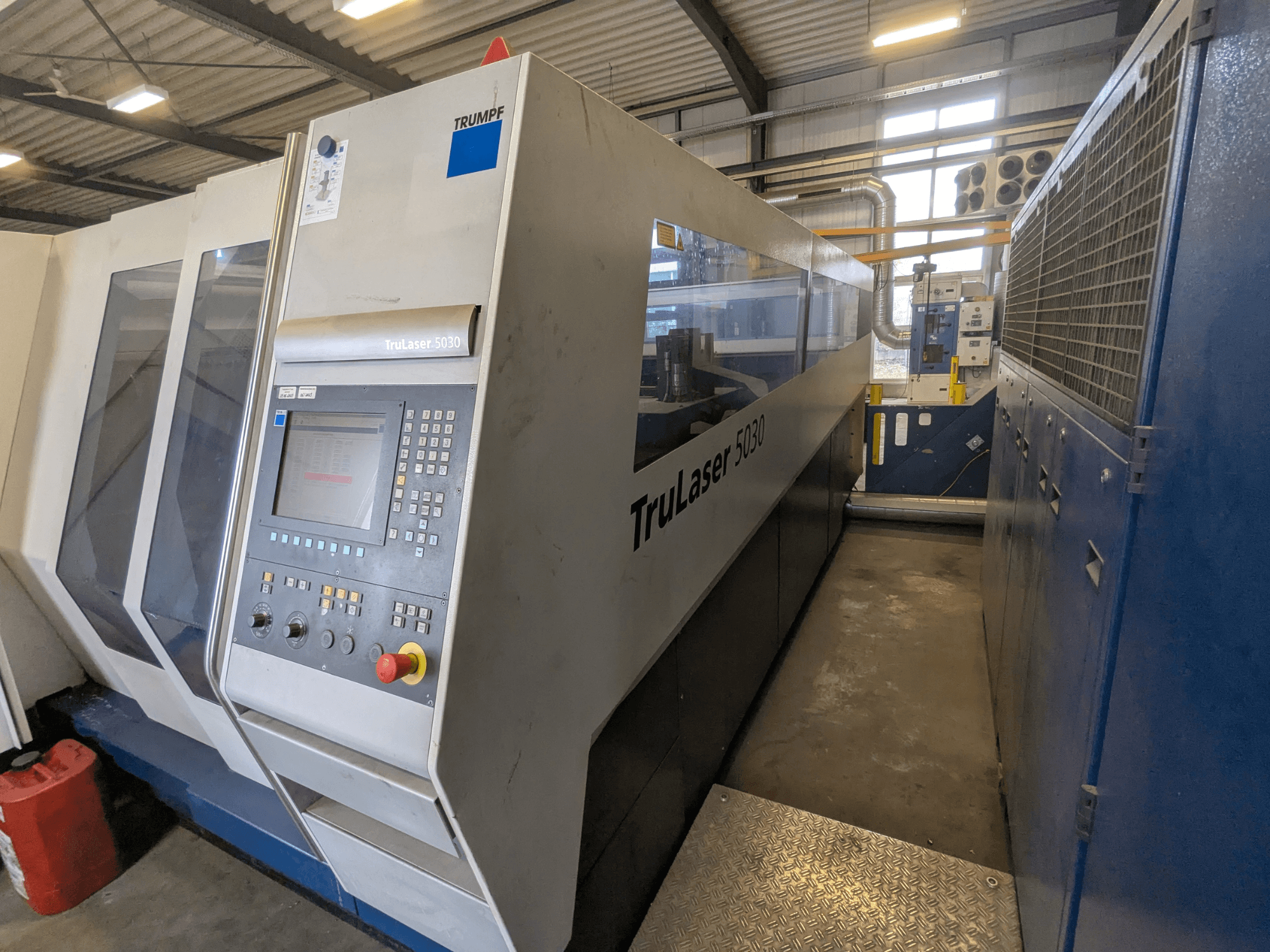 TRUMPF TruLaser 5030 CO2-laserlõikepink, esiplaanil on juhtpaneel ja elegantne disain, tööstuslikus keskkonnas.