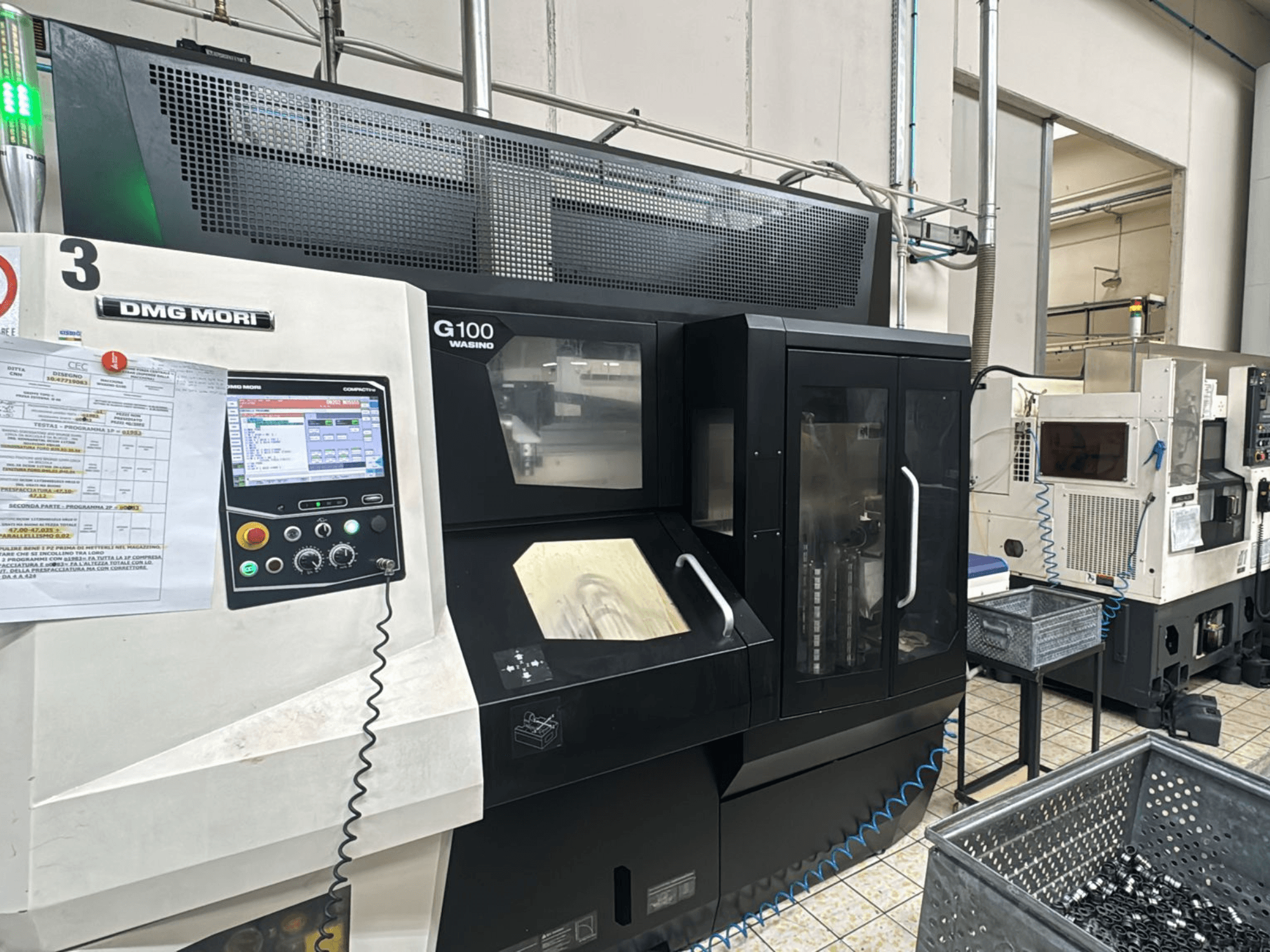 DMG MORI G100 masin tehases, esivaade, millel on digitaalne juhtpaneel ja lähedal asetsevad tööriistakastid.