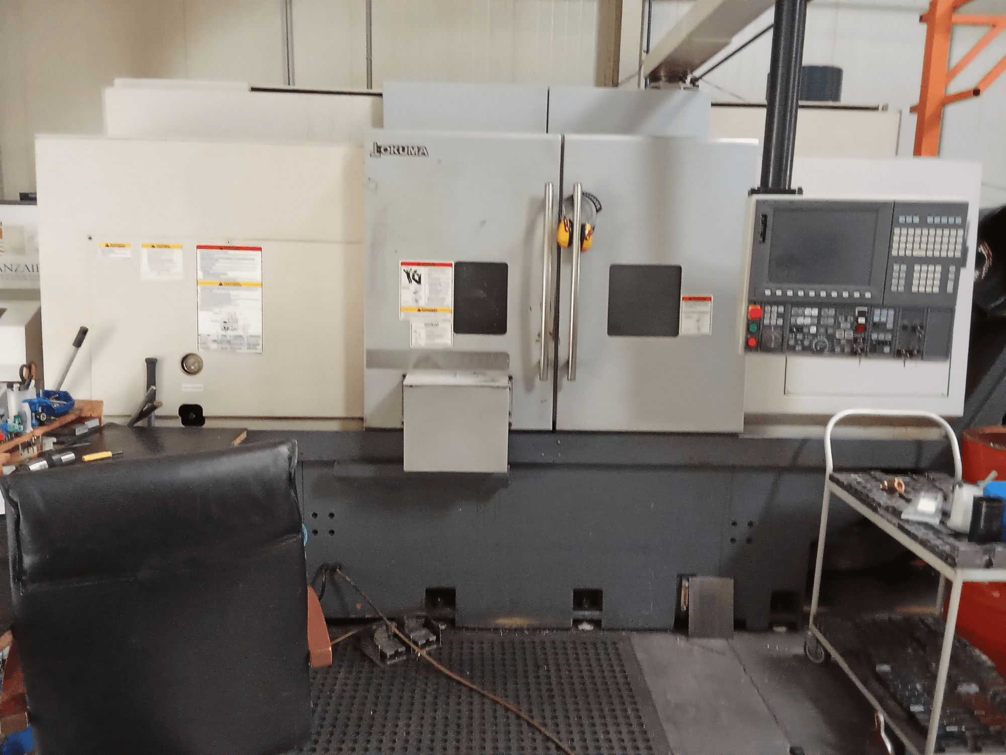 Okuma Genos L300 E-M horisontaalne treipink eesvaates, kus on näidatud juhtpaneel ja kaks ust, mis on paigutatud töökojakeskkonda.