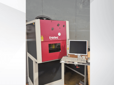 Punane Trotec Laser-Work-Station vaadatuna eestpoolt, millel on tööjaamal monitor ja klaviatuur.