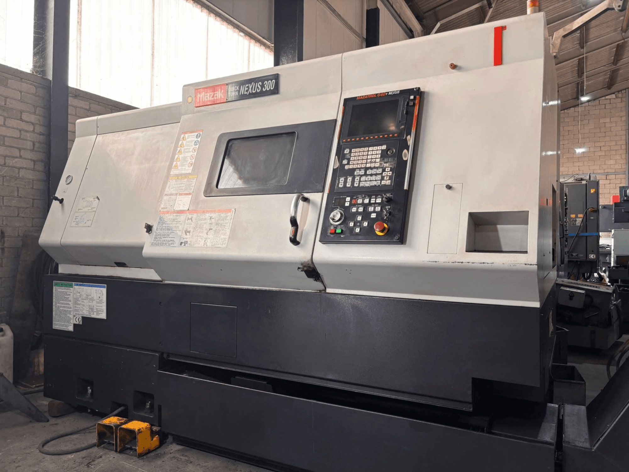 Mazak QT NEXUS 300 horisontaalne treipink, külgvaade, millel on näha juhtpaneel ja töönäidikud töökoda keskkonnas.