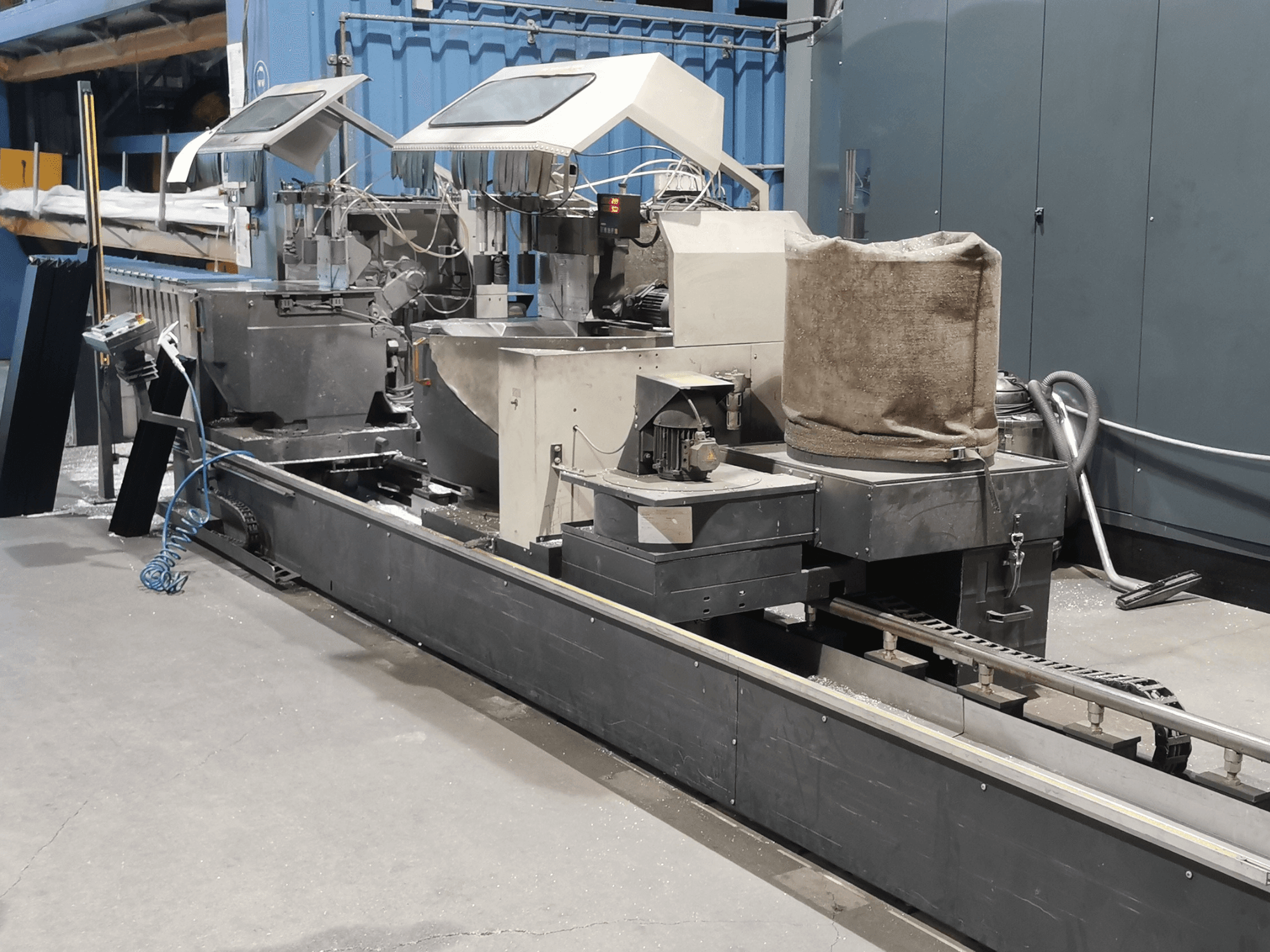 Tööstuslik töötlemismasin küljelt vaadatuna, millel on punkrid, konveierilint ja juhtpaneel tehases.