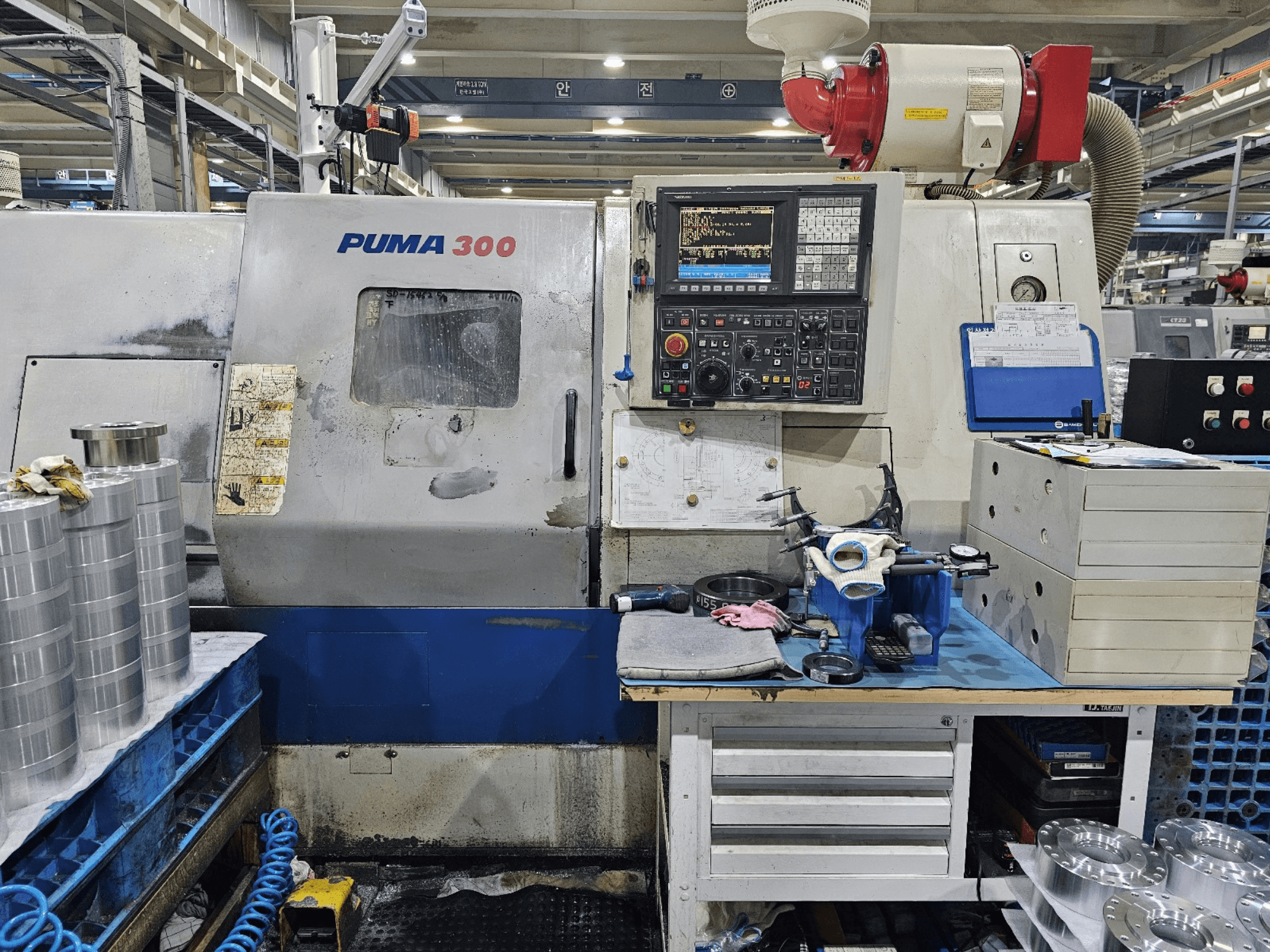 PUMA 300 CNC-tööpink töökojas; esiplaanil on juhtpaneel, tööriistad ja metallosad tööpinkidel.