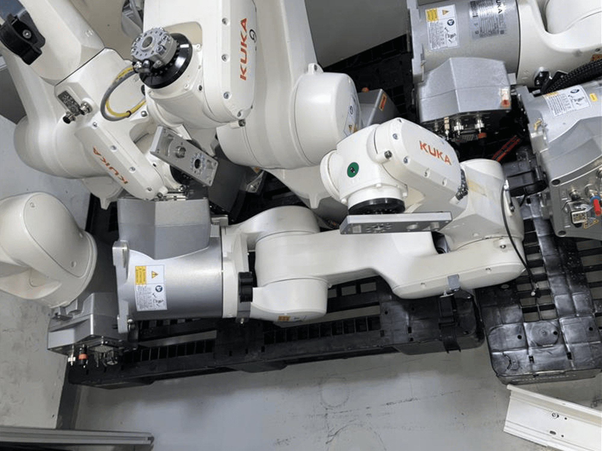 KUKA KR 6 R900 CR robotkäsi ülaltvaates, millel on mitu liigendit ja mootorit ning mis on paigaldatud mustale alusele koos kaablitega.
