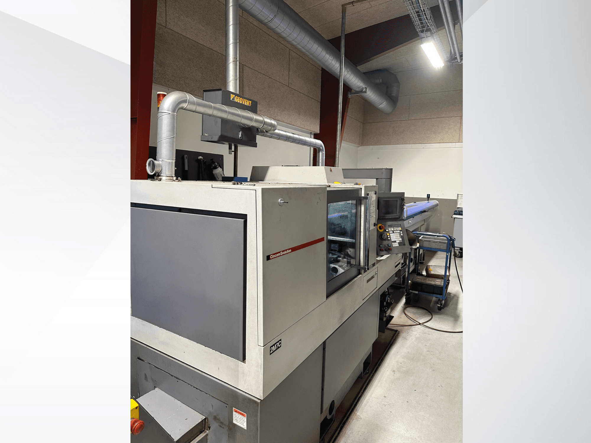 MVC kaubamärgi tööstuslikud masinad, külgvaade, kus on näha juhtpaneel ja kanalid, mis on paigutatud tehasekeskkonda.