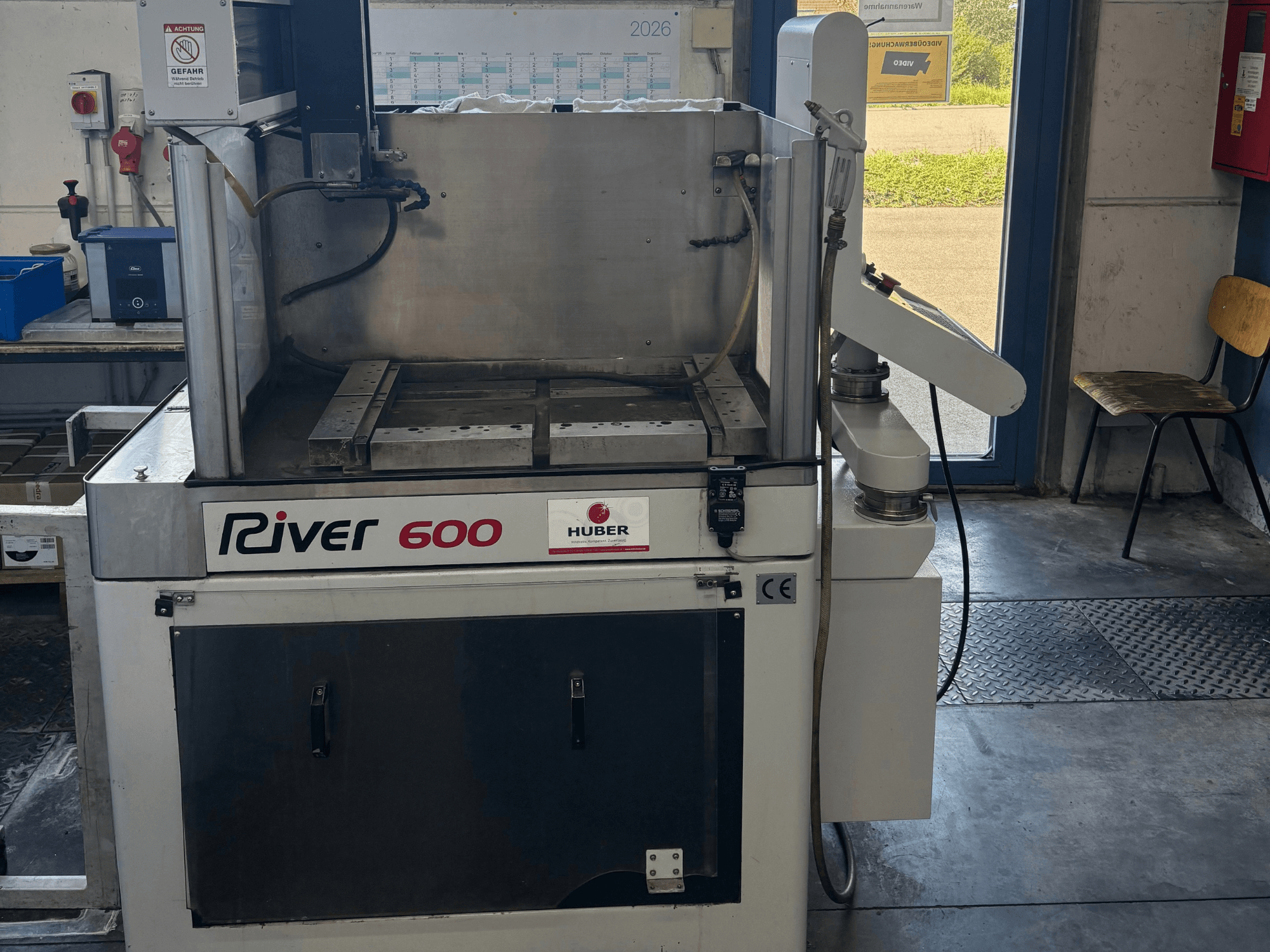 HUBER River 600 CNC sügavuslõikamise EDM-masin, vaade eest, millel on osaliselt avatud töökamber ja juhtpaneel.