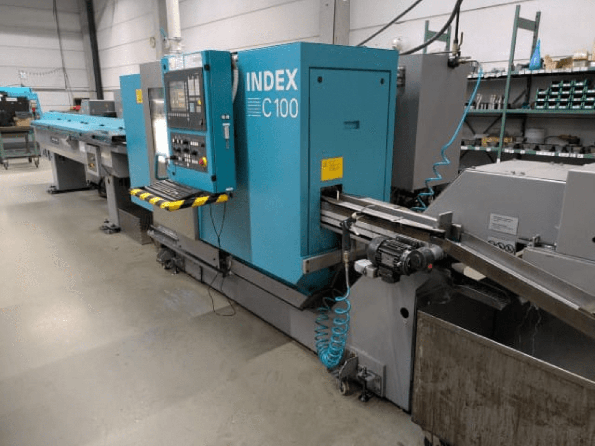 Index C100 horisontaalne treipink, külgvaade; varustatud juhtpaneeli, etteandmissüsteemi ja metallilaastude kogumiskastiga.