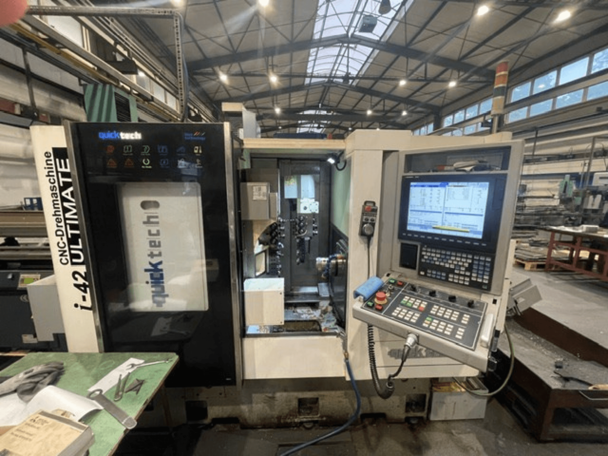 Quick-Tech I-42U Šveitsi tüüpi treipingi esivaade, kus näidatakse juhtpaneeli ja CNC-liidest töökojas.