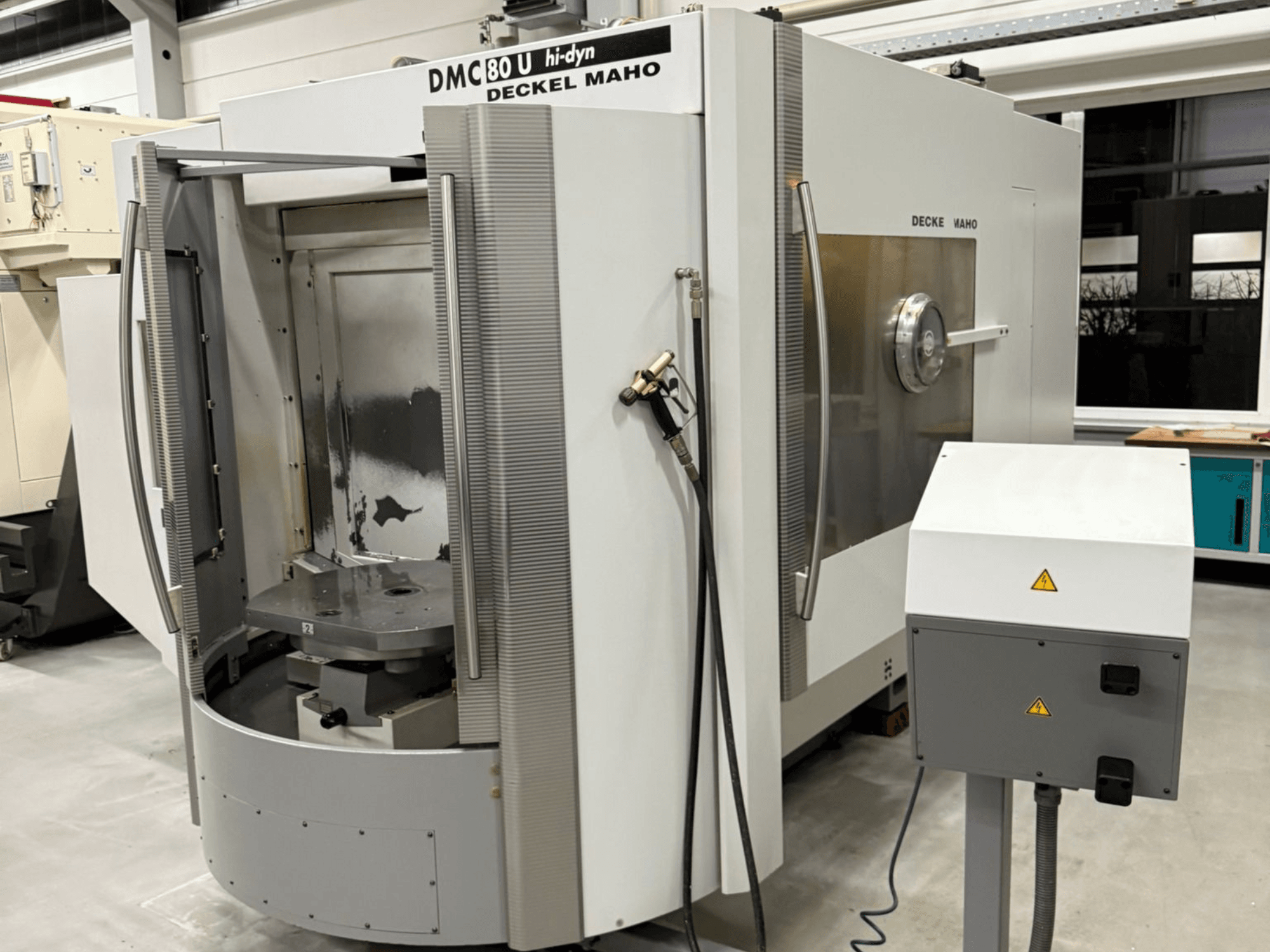 Deckel Maho DMC 80 U kiire CNC-freespingi esivaade, mille küljel on avatud ligipääsuuks ja juhtpaneel.
