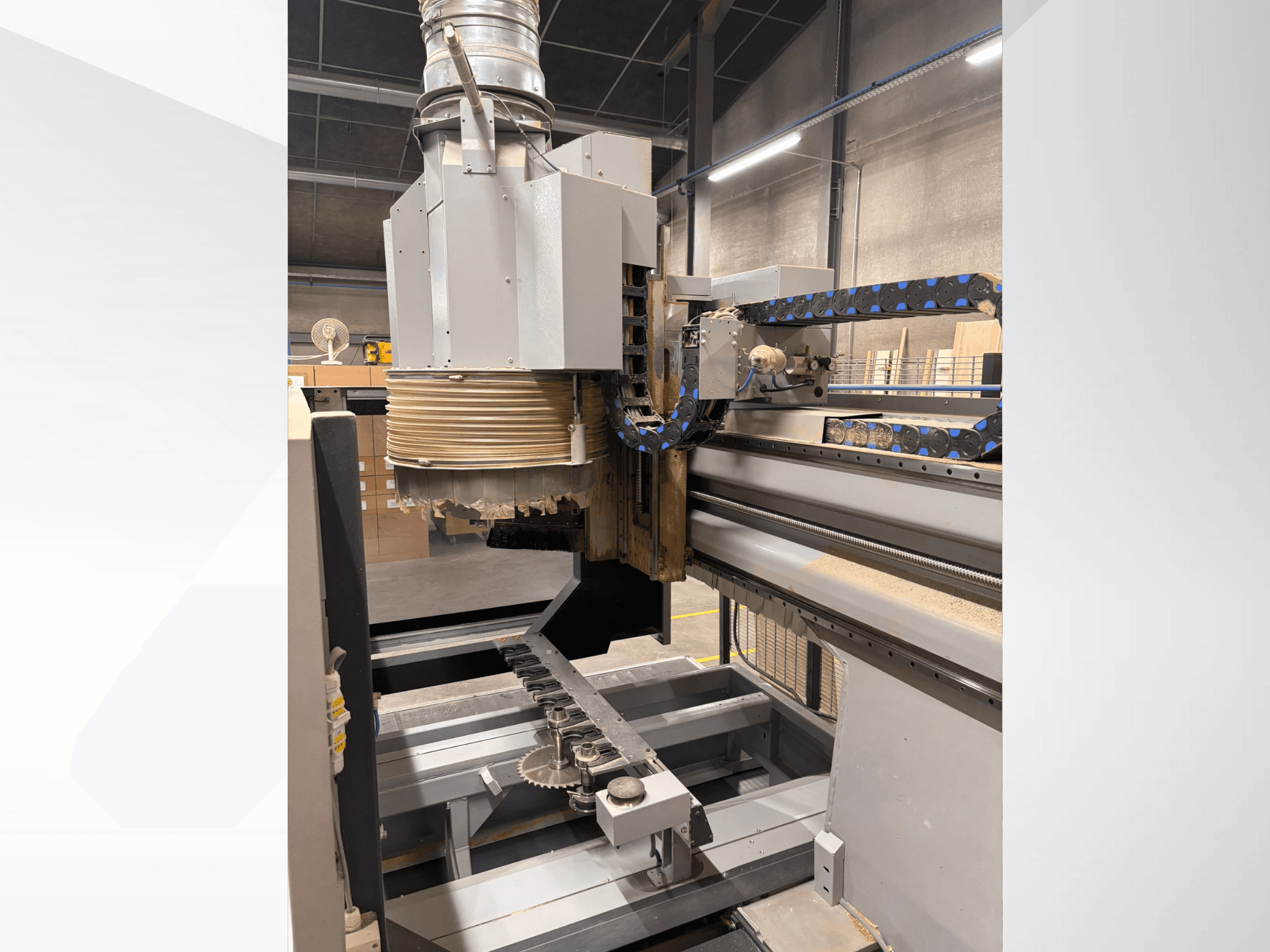 Suure spindli ja konveieriga CNC-freespingi külgvaade, millel on kujutatud puidulõikeriistad ja masinaosad.