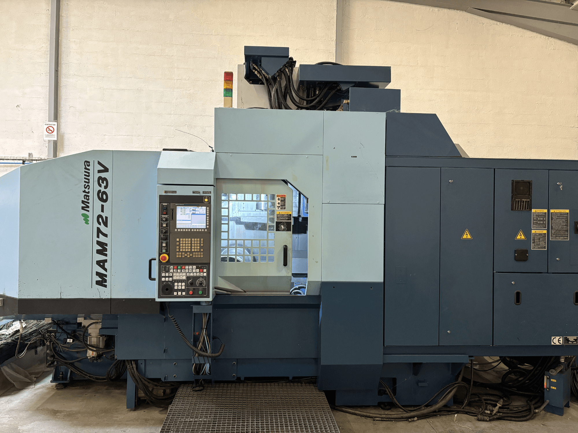 Matsuura MAM 72-63 V vertikaalne töötluskeskus, esiplaanil on juhtpaneel ja ohutusseadmed.