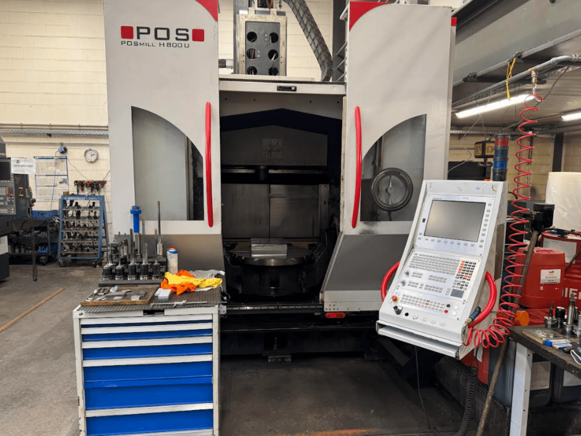 POSMILL H800 U CNC-tööpingi vaade eestpoolt, kus on näha juhtpaneel ja tööpiirkond koos tööriistade ja seadmetega lähedal.
