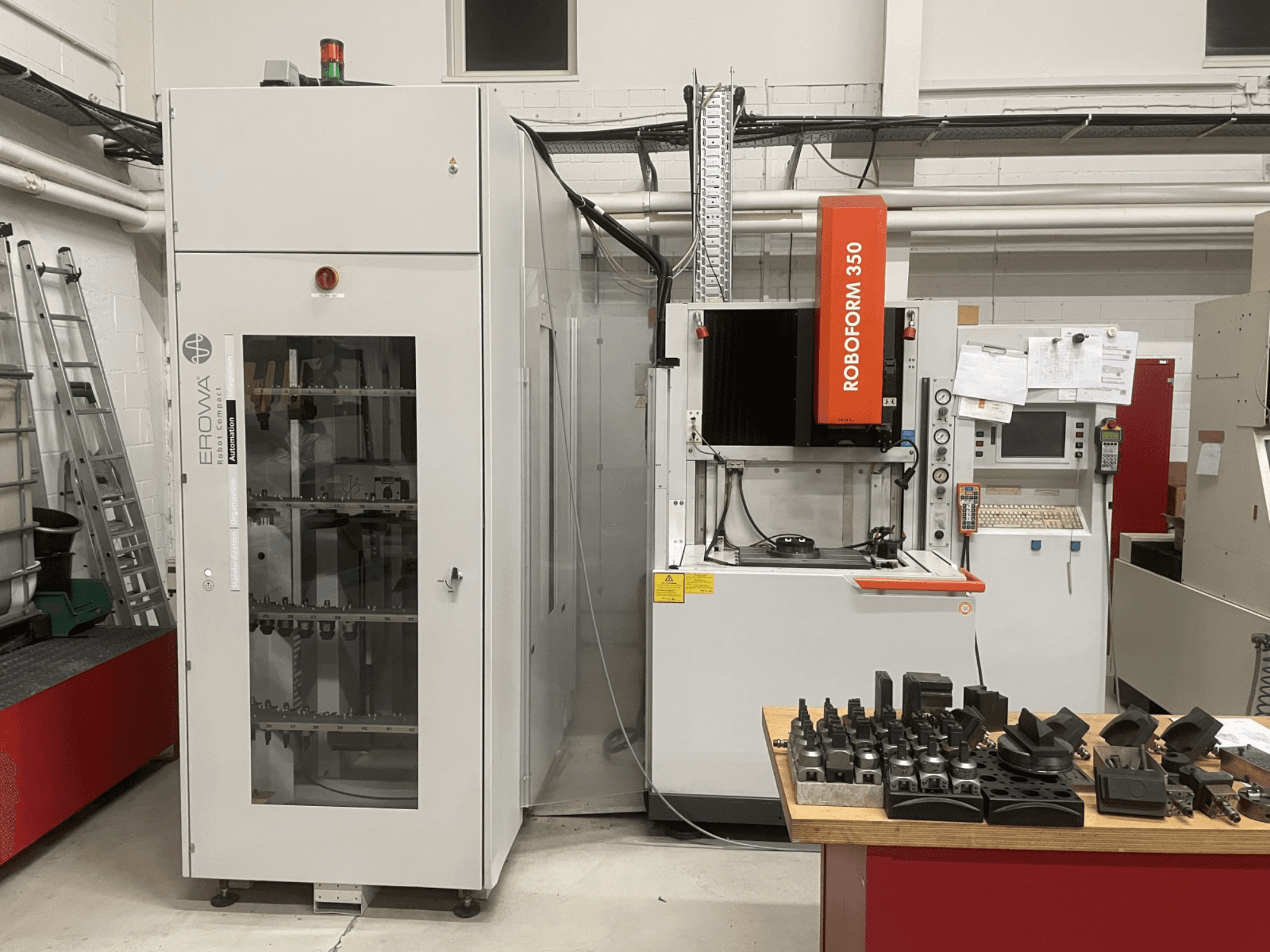 Sinkpinkimispingi CHARMILLES Roboform 350, esiplaanil, koos laual olevate tööriistadega ja kõrvalolevate seadmetega.