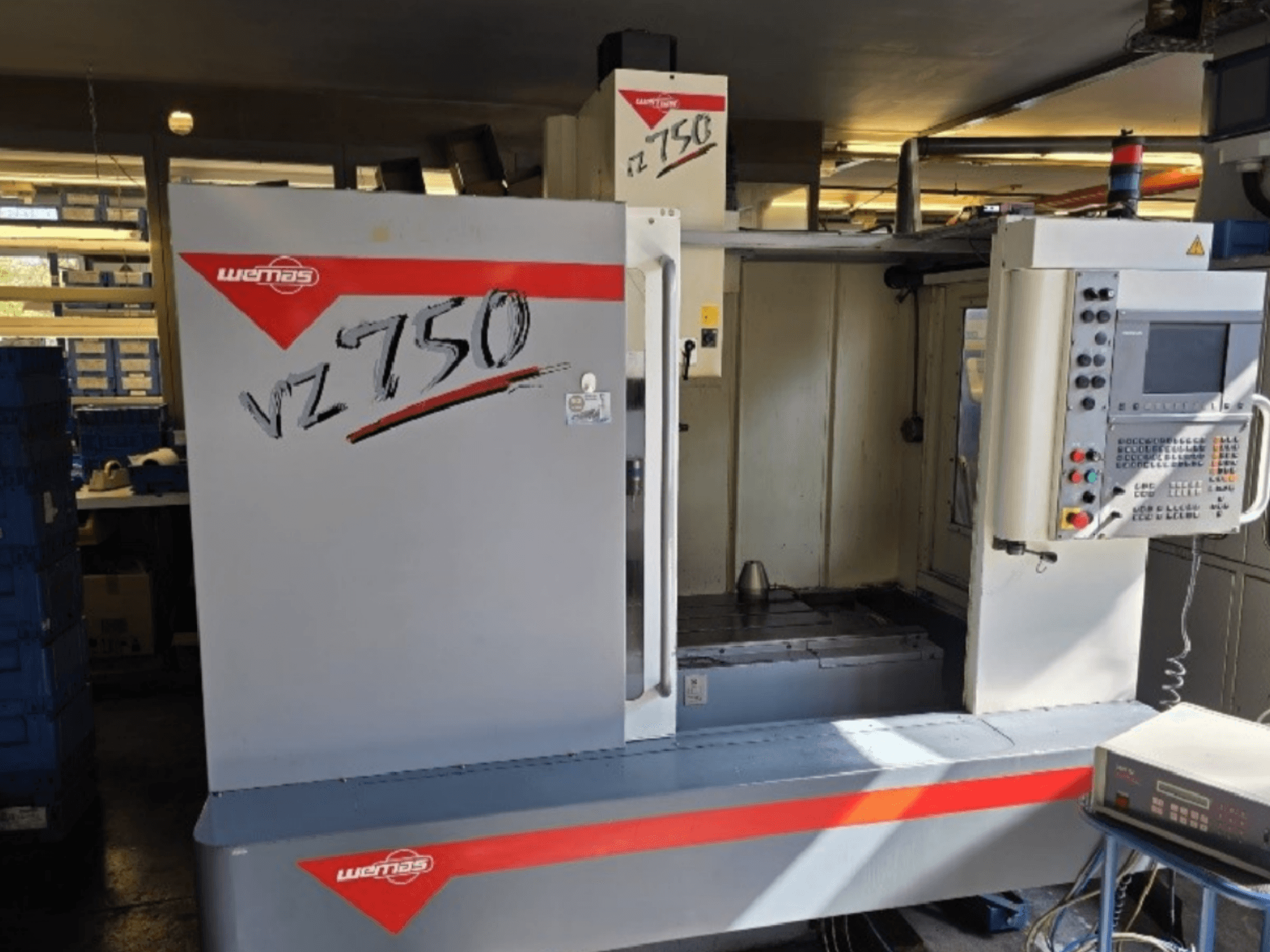 WEMAS VZ 750 CENTURY vertikaalne töötluskeskus, esiplaanil on juhtpaneel ja tööruum.
