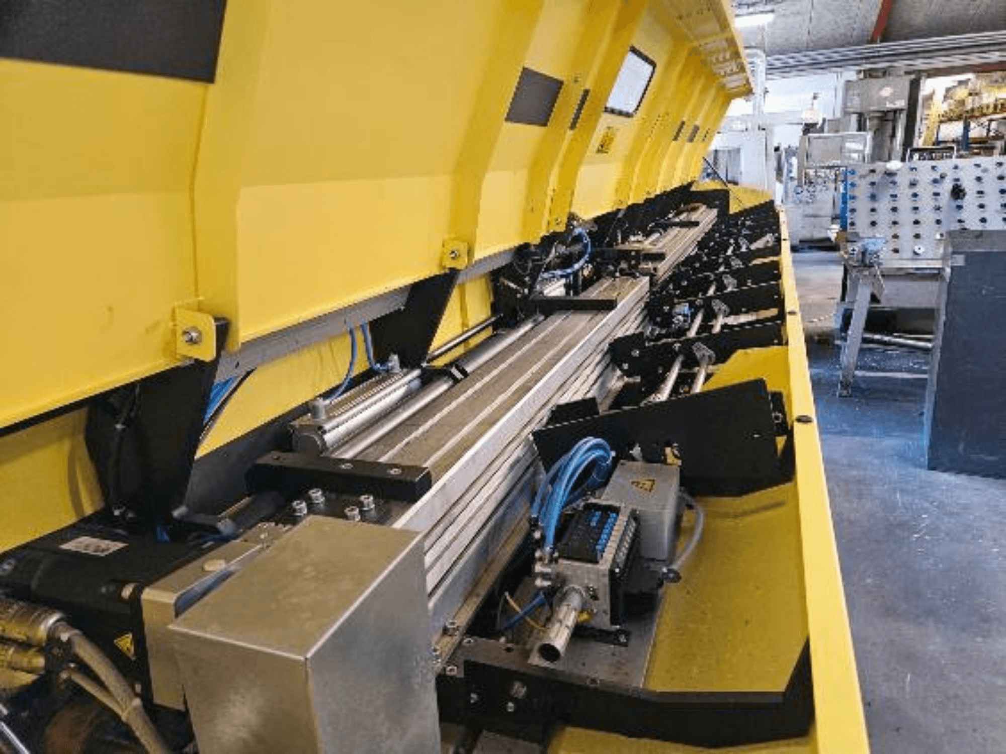 Lähivaade kollasele hüdraulilisele masinale, millel on metallosad ja konveierirööpad, millel on voolikud ja elektroonilised osad.