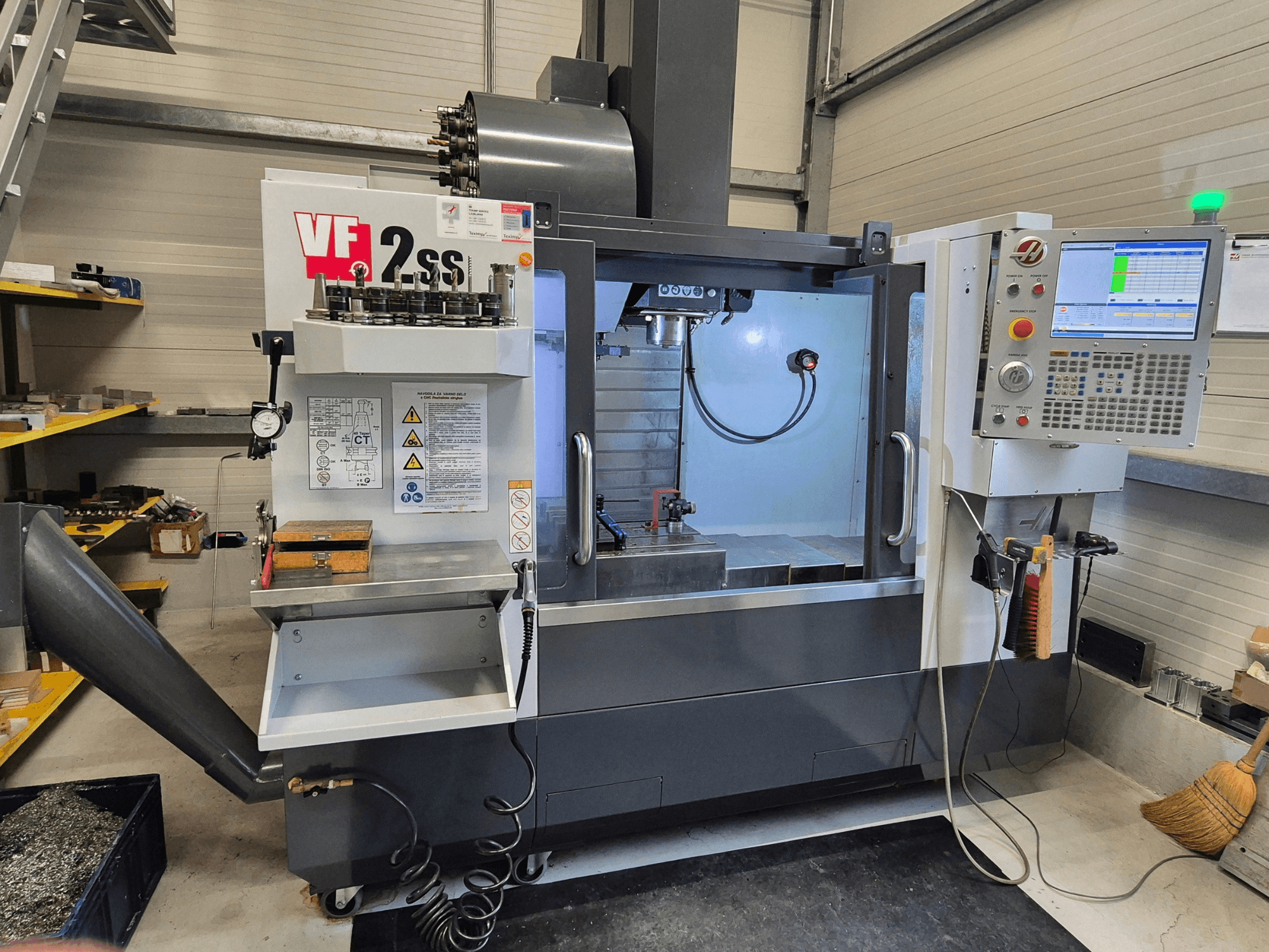 HAAS VF2 SS-EU vertikaalne töötlemiskeskus esiplaanil, kus on näha juhtimisseadmed, spindel ja töötlemisala.