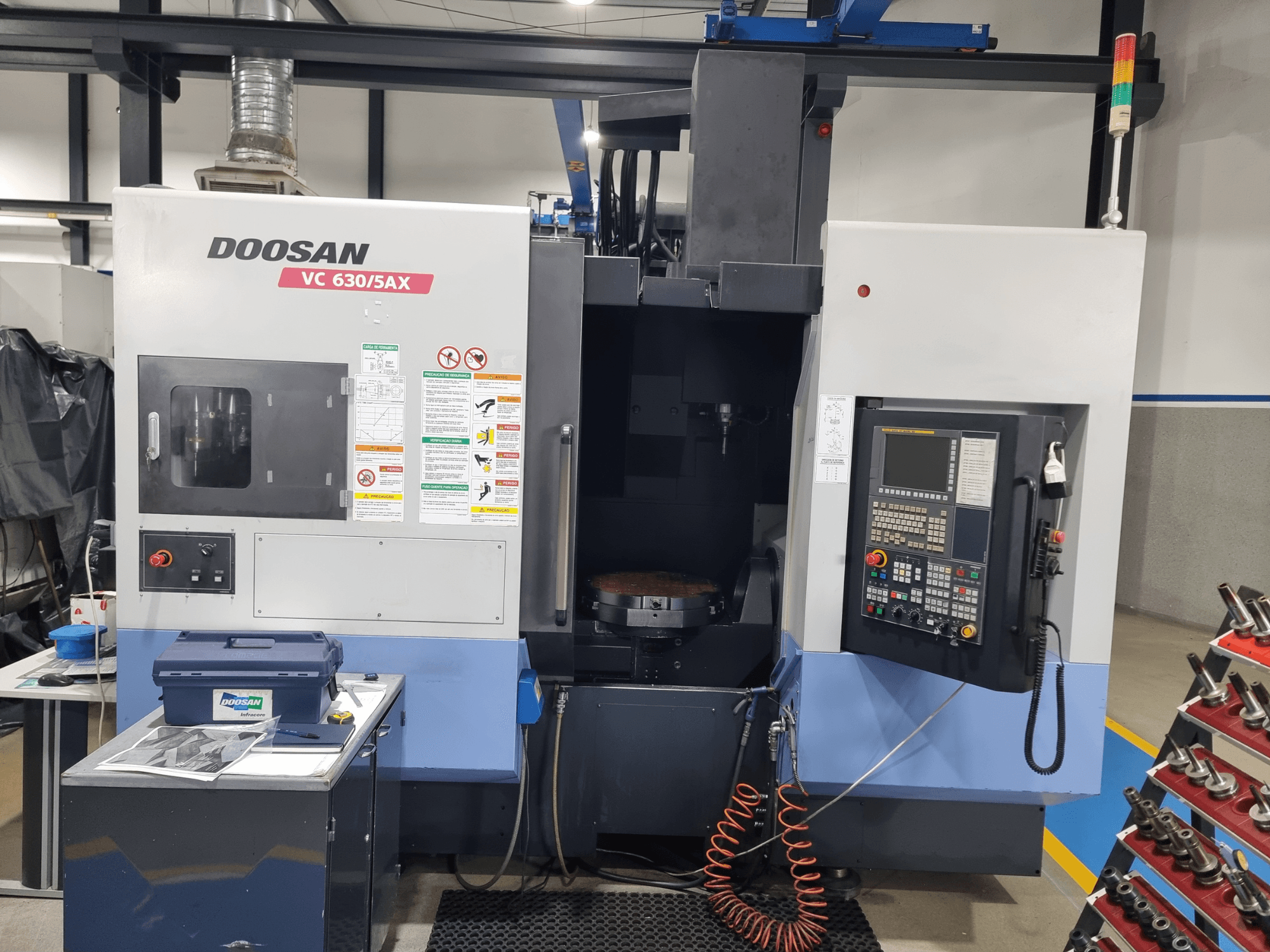 DOOSAN VC 630/5AX universaalne töötlemiskeskus, esivaade, millel on näha juhtpaneel, töötlemisala ja ohutusseadmed.