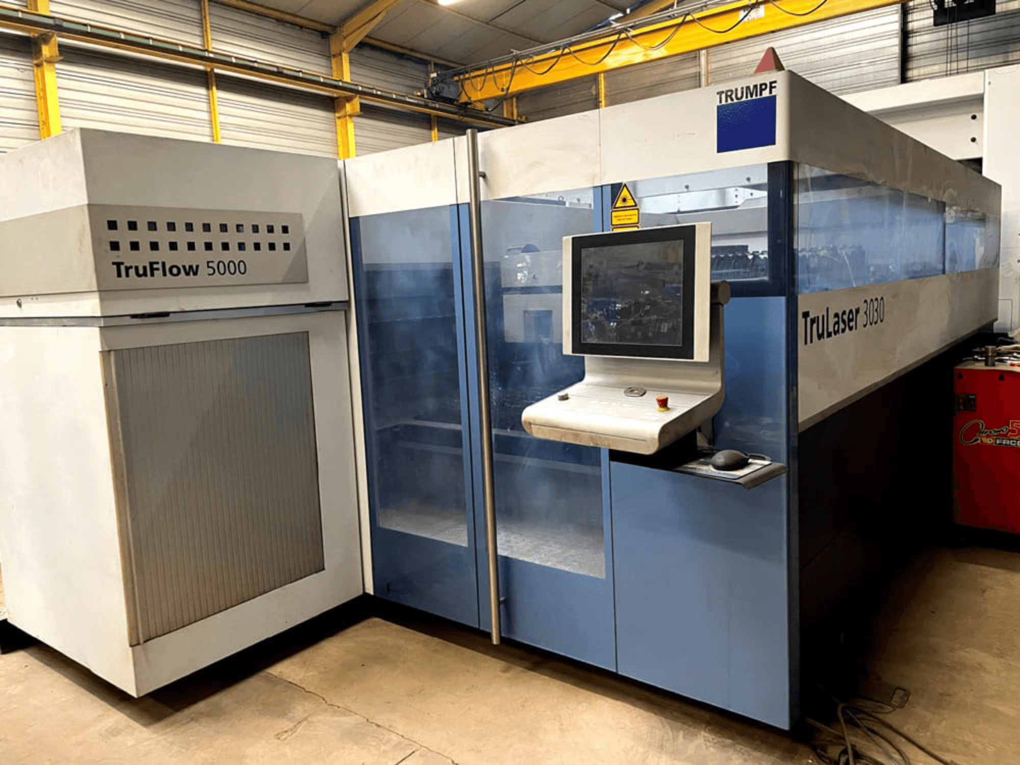 TRUMPF TruLaser 3030 CO₂-laserlõikur eestvaates, millel on juhtpaneel ja selle kõrval asuv TruFlow 5000 seade.
