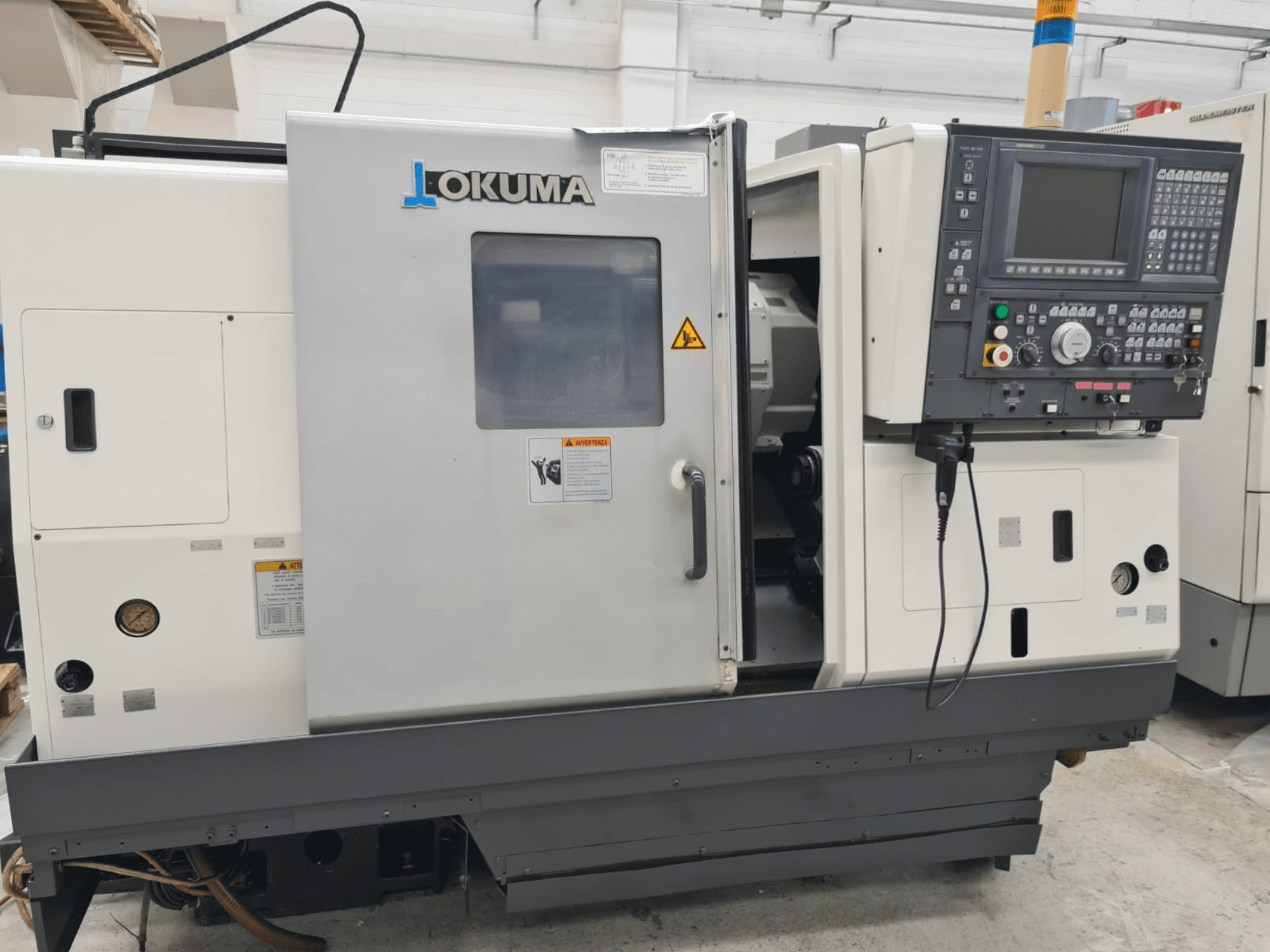 Okuma LB 300M X 500 horisontaalne treipingi külgvaates, kus on näidatud juhtpaneel, juurdepääs spindlile ja ohutushoiatused.