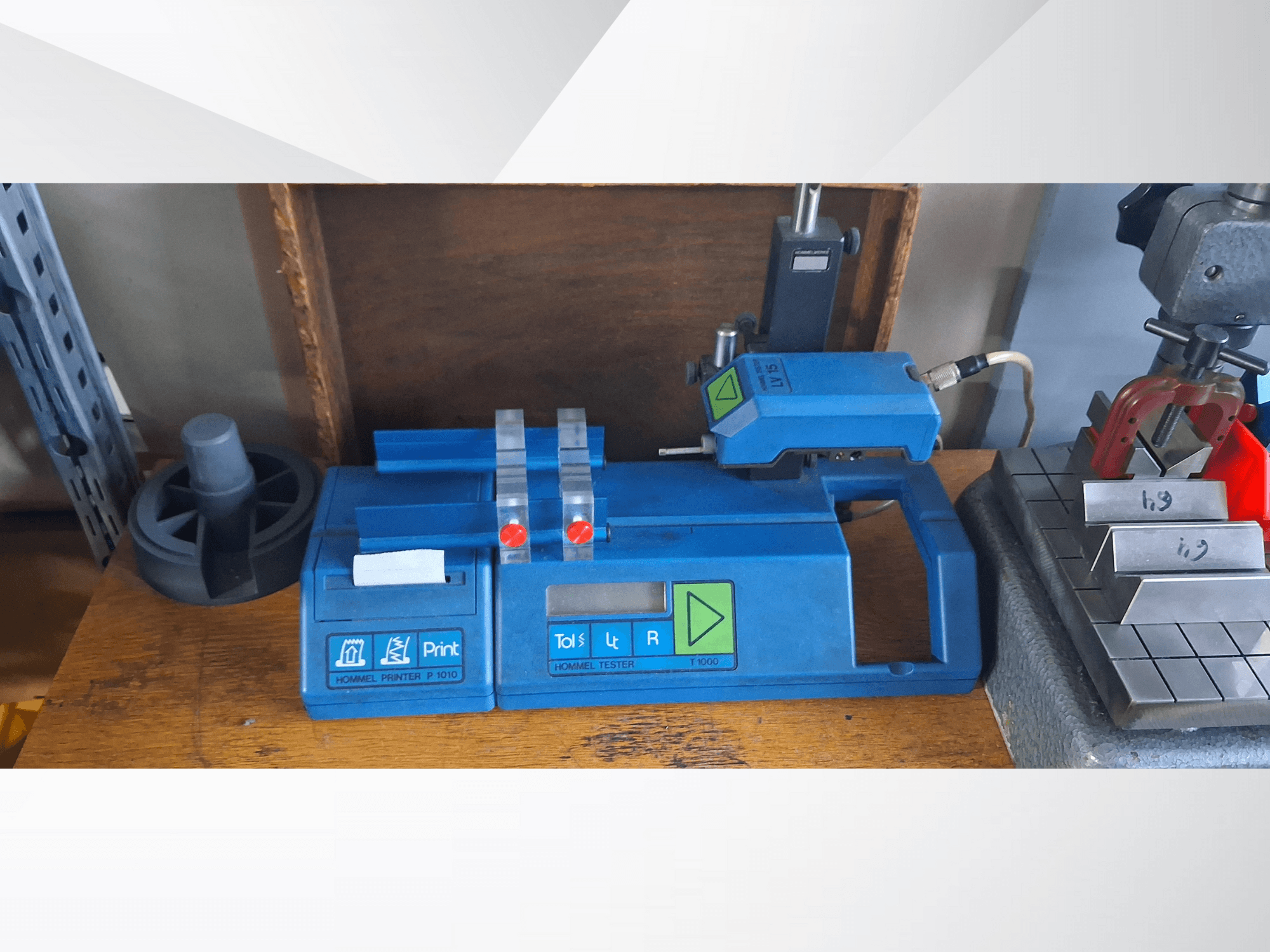 Hommel Printer P 1010 ja Tester T1000 külgvaates, sinise korpuse, nuppude ja punaste näitajatega, töölaual.