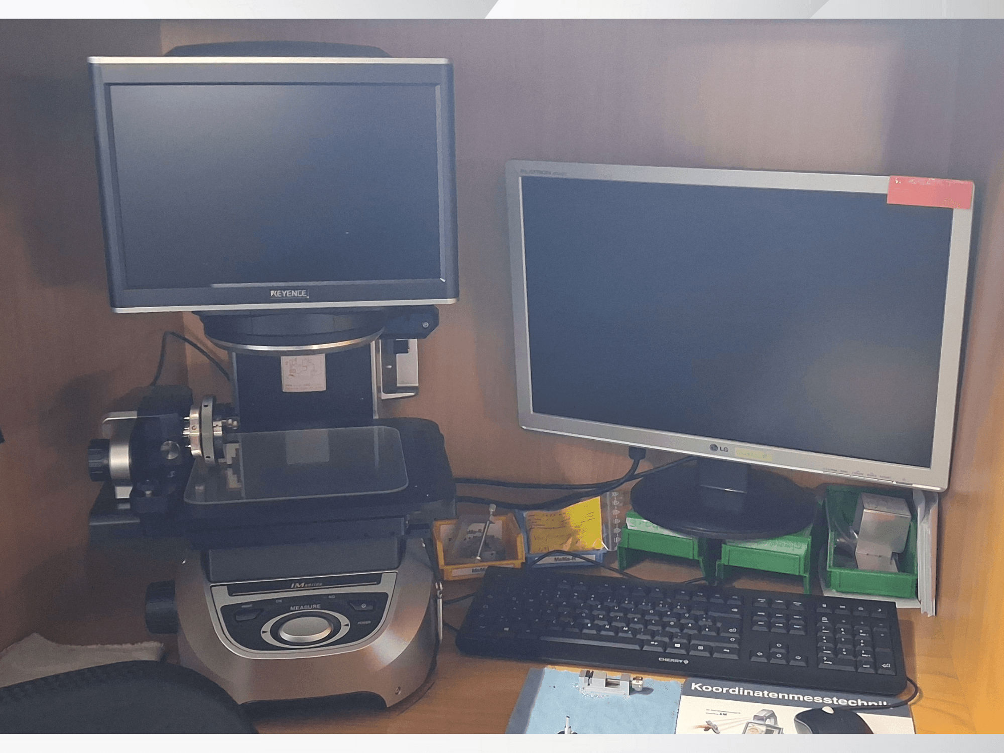 Keyence'i mõõtesüsteem kahe monitoriga (üks LG, teine Keyence) ja klaviatuuriga, esiplaanilt vaadatuna.