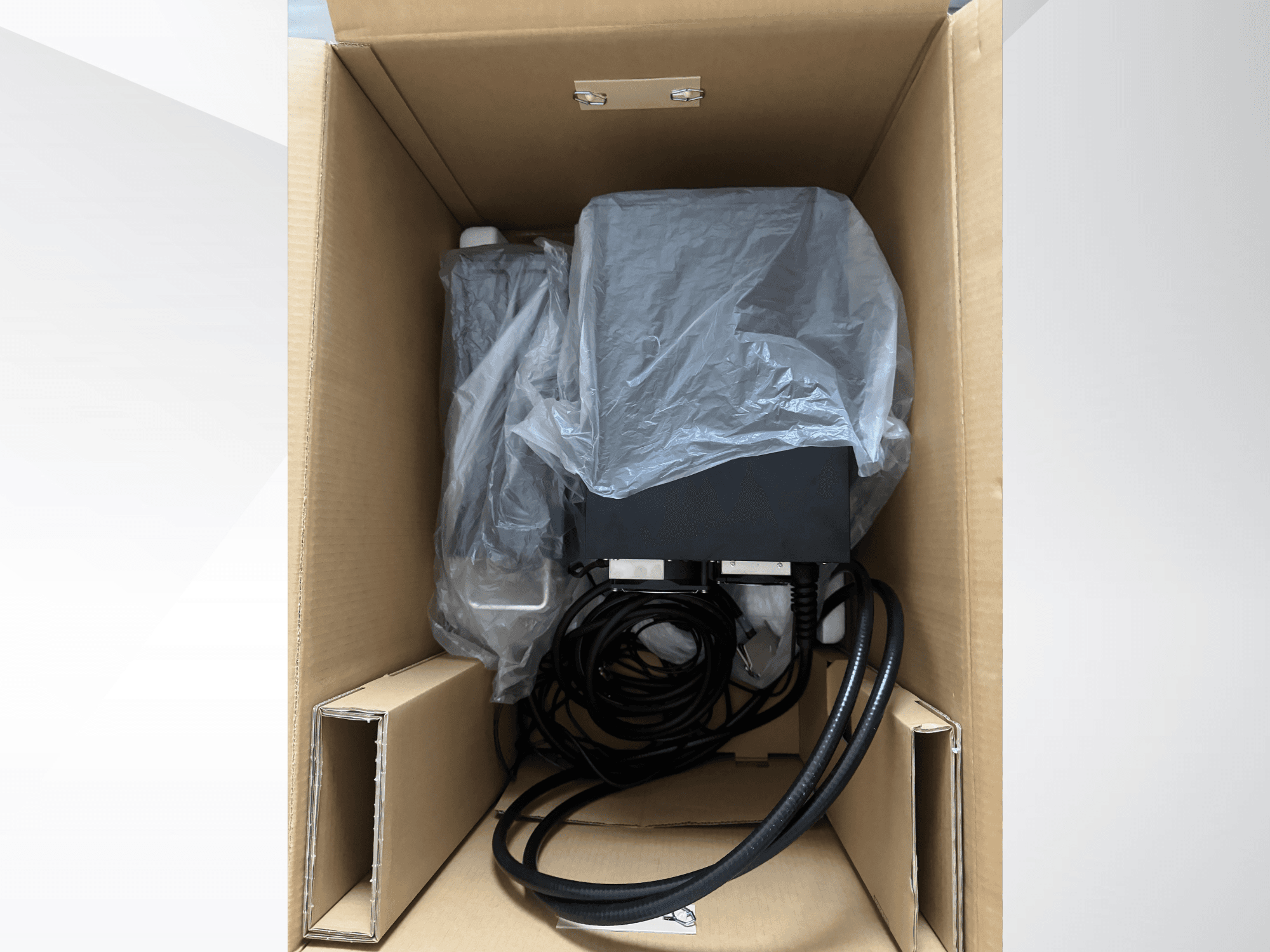 KEYENCE MD-X2500A lasermärgistusaparaat pappkarbis, osaliselt kilega kaetud, millel on näha kaablid ja komponendid.
