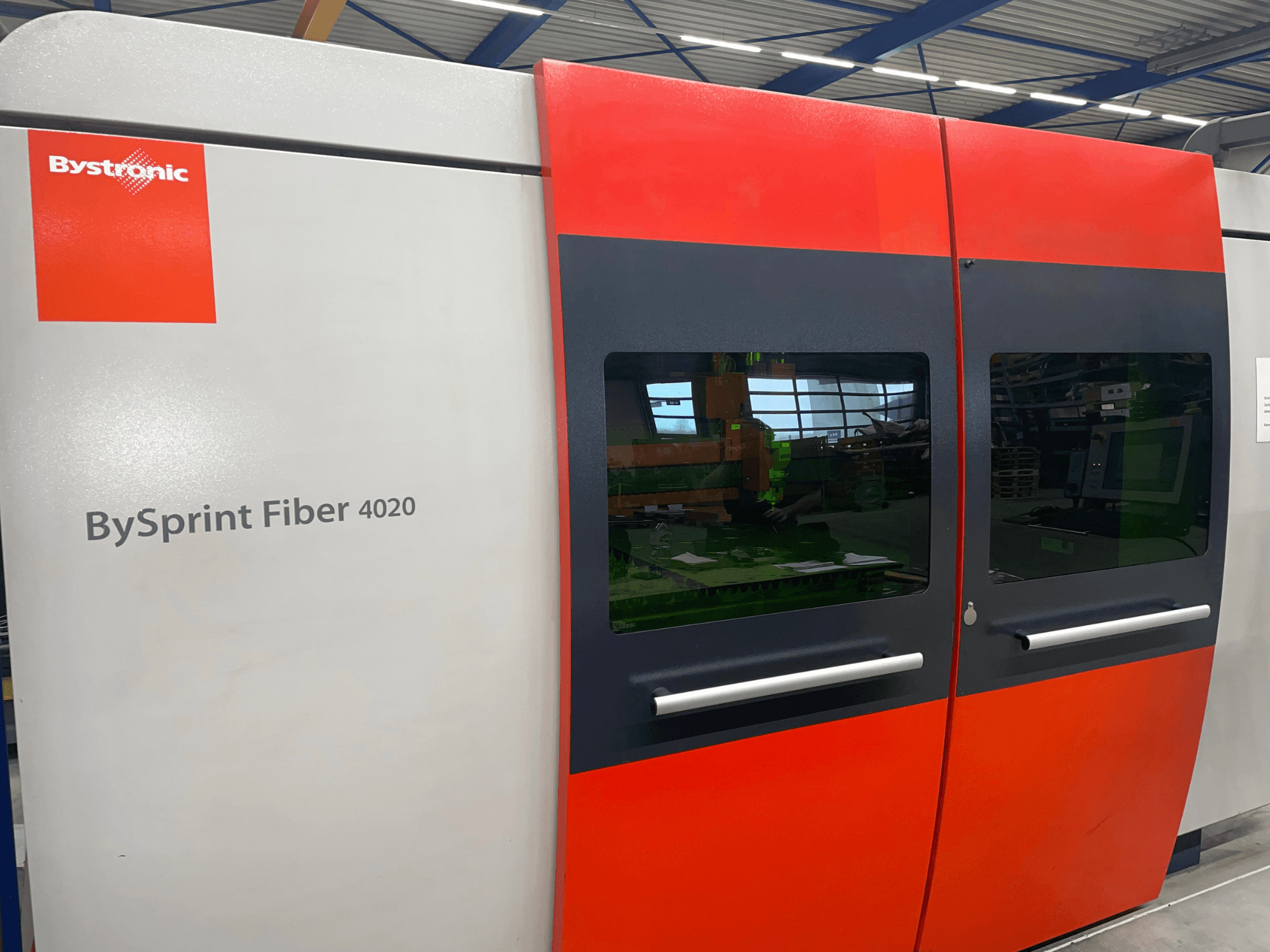 Bystronic BySprint Fiber 4020 esiplaanil, millel on hall ja punane paneel, mille sees on näha suured aknad ja juhtimisliides.