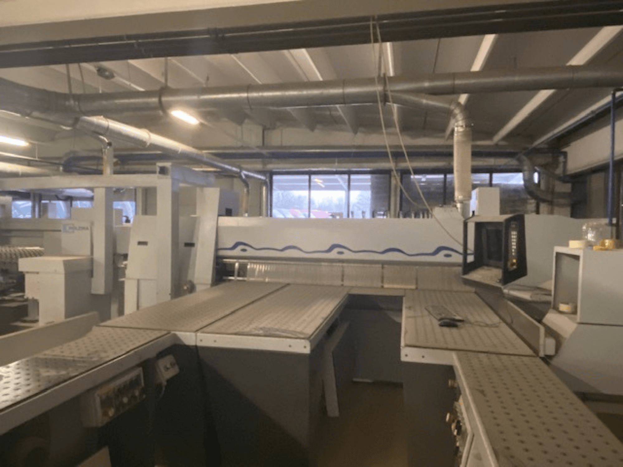 Tööstuslik tööruum, kus on masinad koos juhtpaneeliga, vaadatuna kõrgendatud nurga alt.