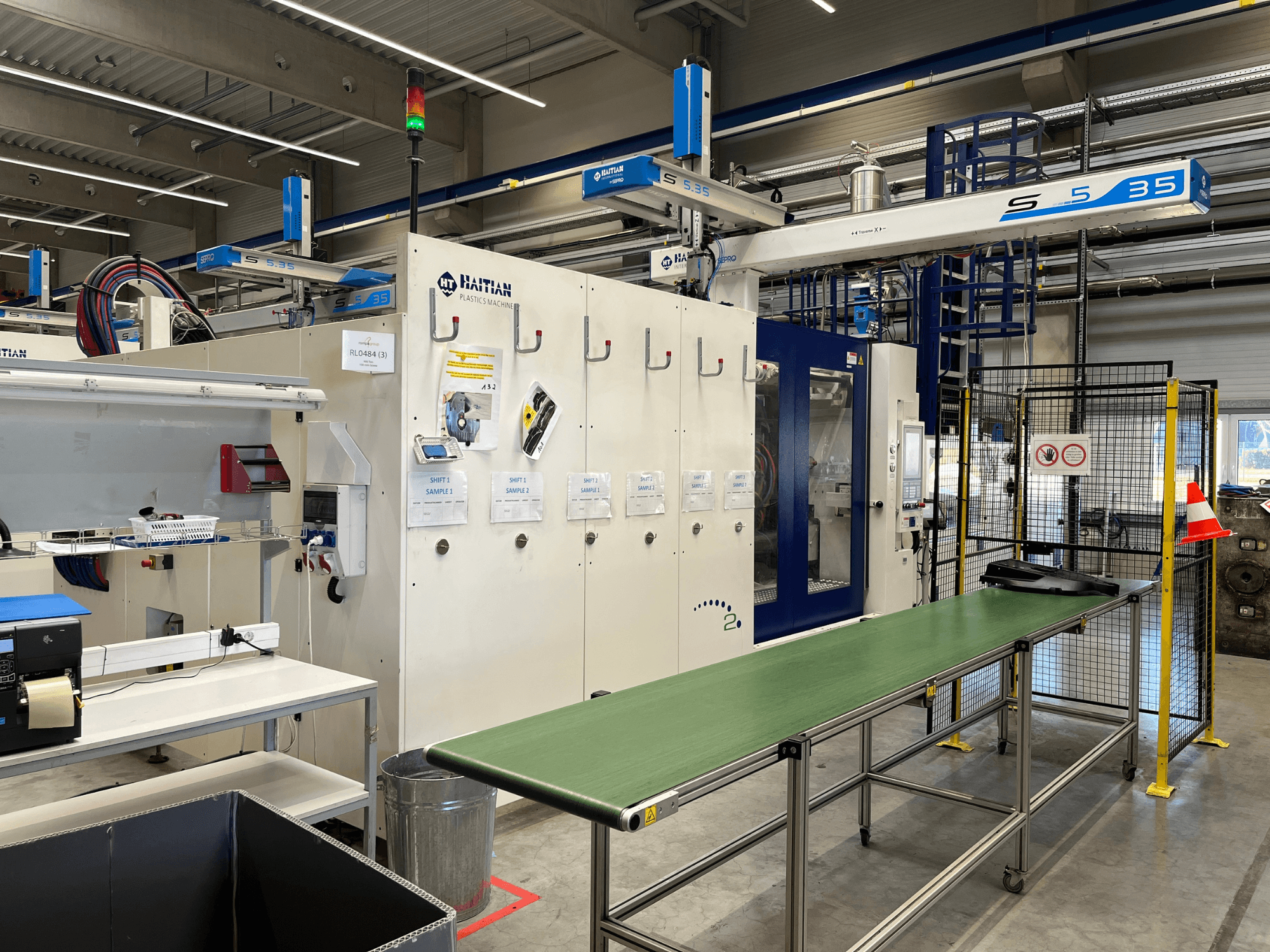 Haiti S5-35 plastmassitöötlemismasin töökojas; esiplaanilt on näha roheline konveierilaud, ohutuspiirdeid ja juhtpaneel.
