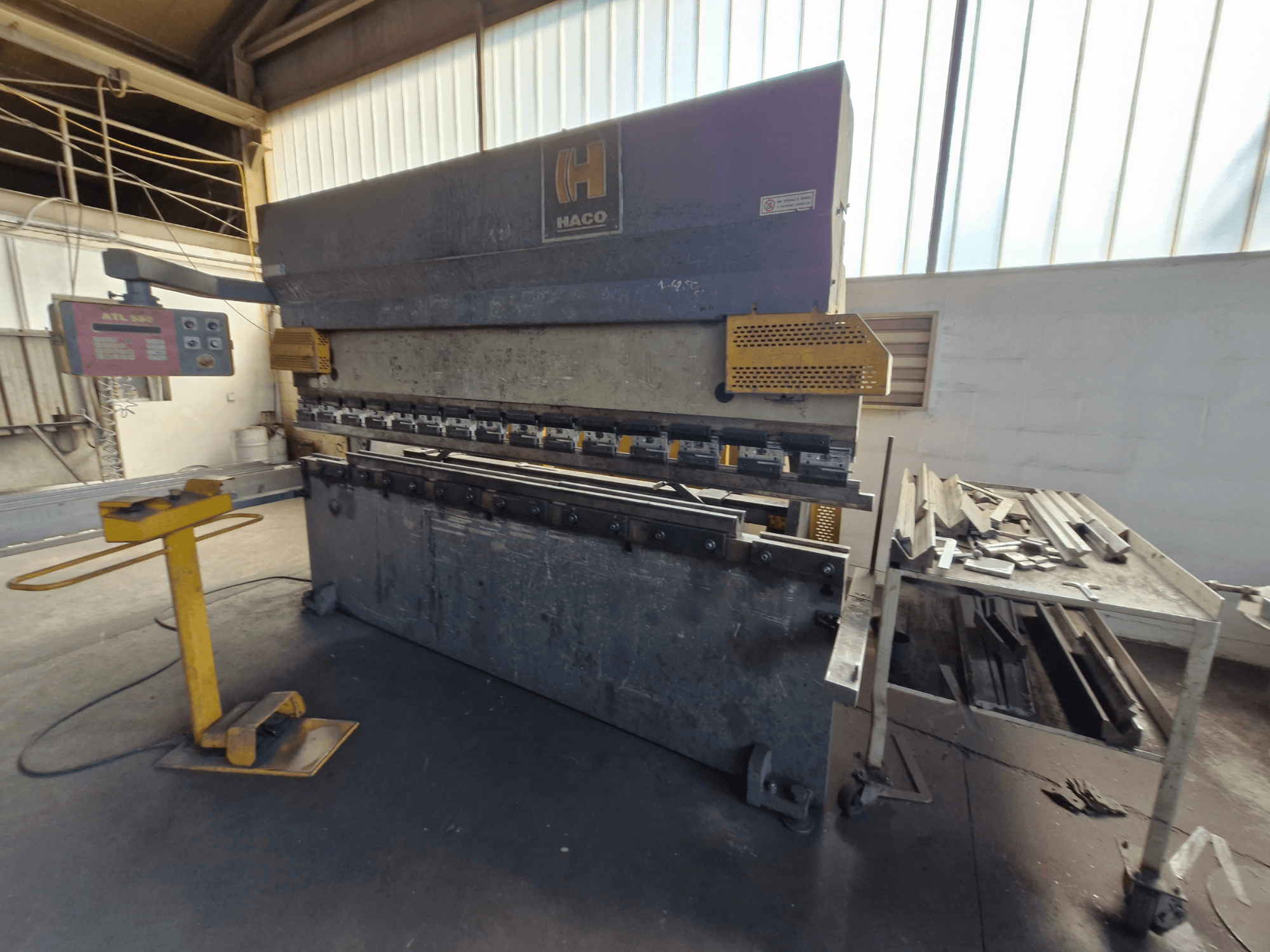 HACO PPM 30135 b presspink töökojas, esiplaanil on juhtpaneel ja metallijäätmed laual selle kõrval.