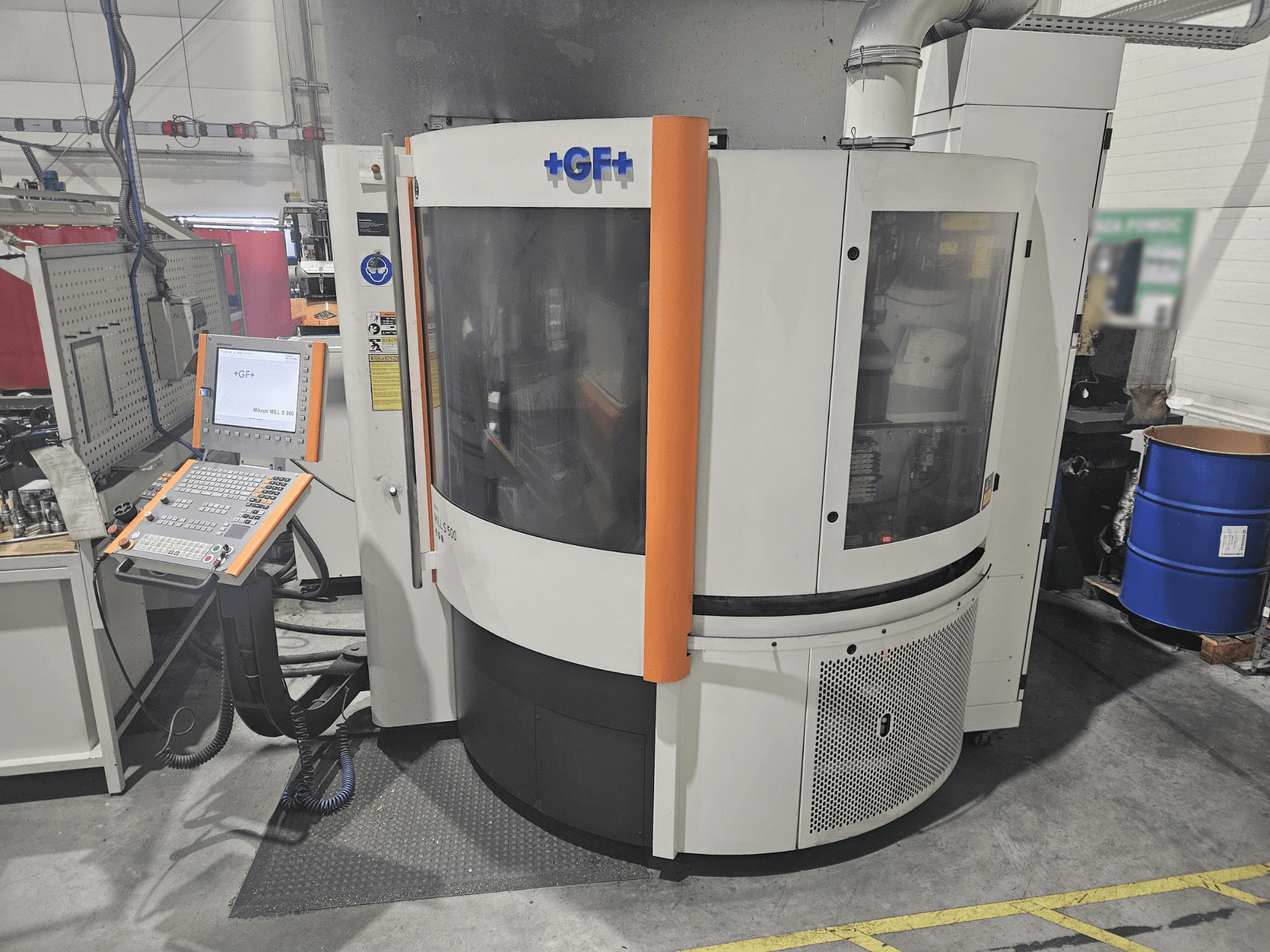 GF Machining Solutions tööpink koos juhtpaneeliga, esivaade; läbipaistev paneel, oranžid aktsendid ja tööstuslik seadistus.