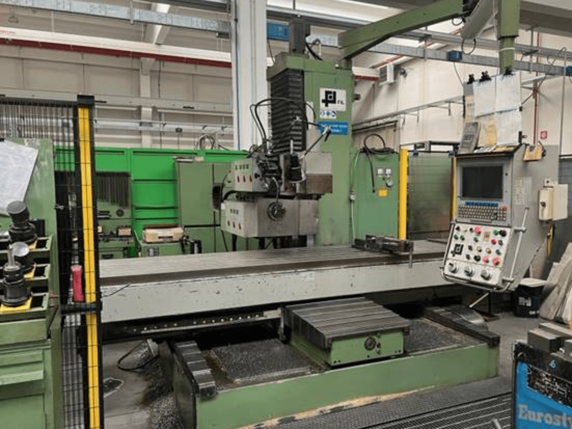 JFLi tööstuslik freespink, esivaade juhtpaneeliga, suur lame laud ja metallilaastud põrandal.