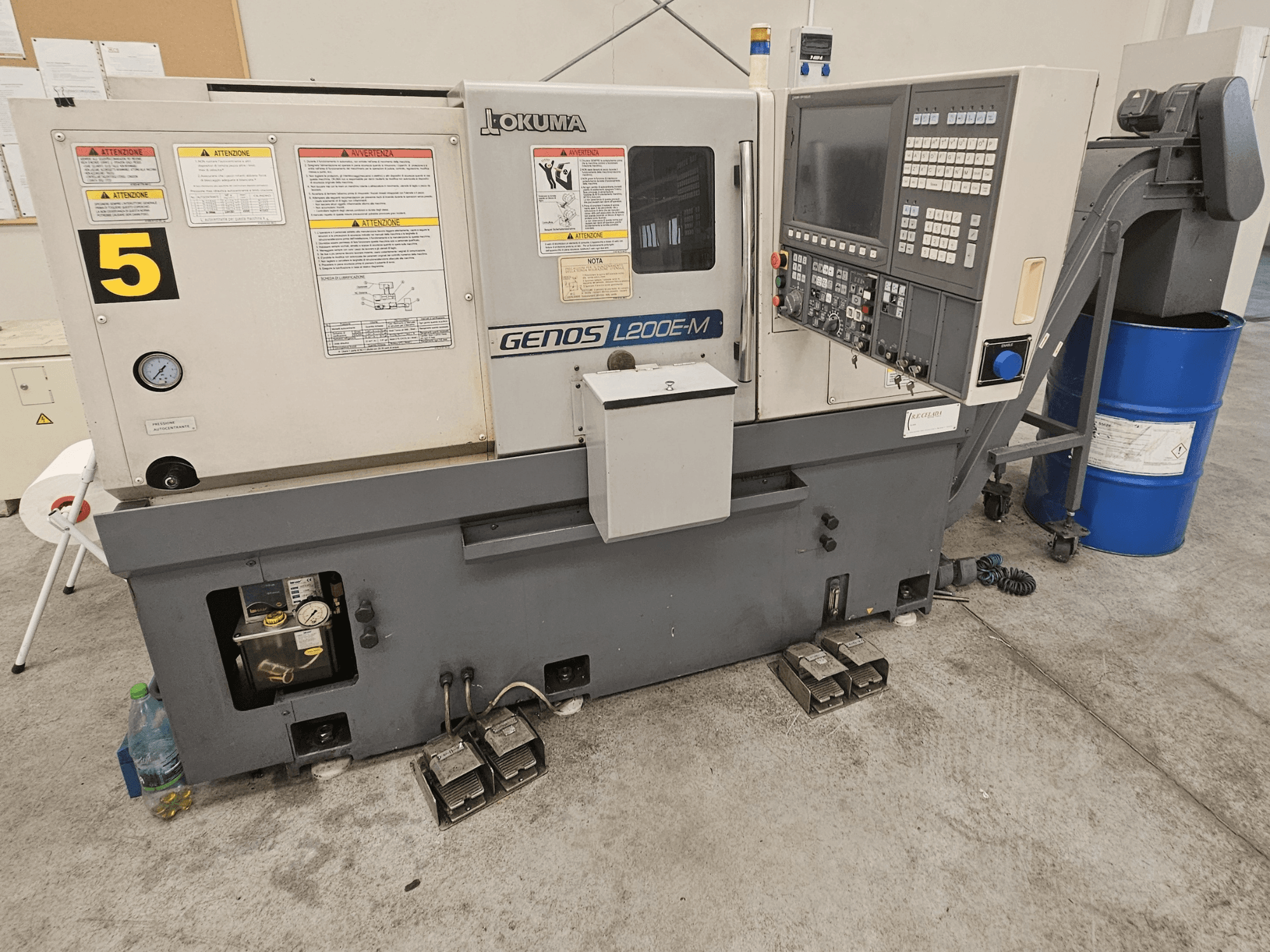 Okuma GENOS L200E-M horisontaalne treipink eesvaates, millel on juhtpaneel, sildid ja jahutusvedeliku tünn.