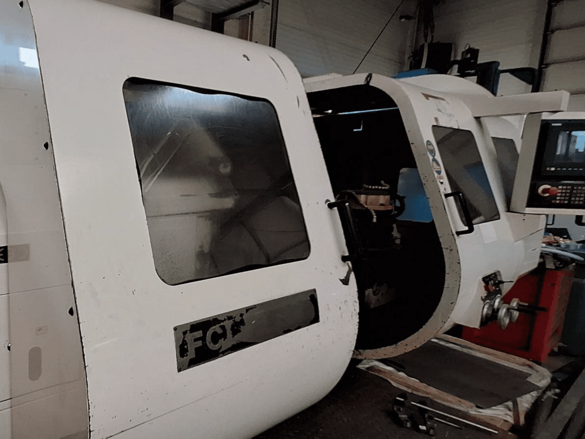 Valge CNC-masin nähtava juhtpaneeli ja avatud uksega, mis näitab sisemisi komponente; esiplaanil. Brändi: FCT.