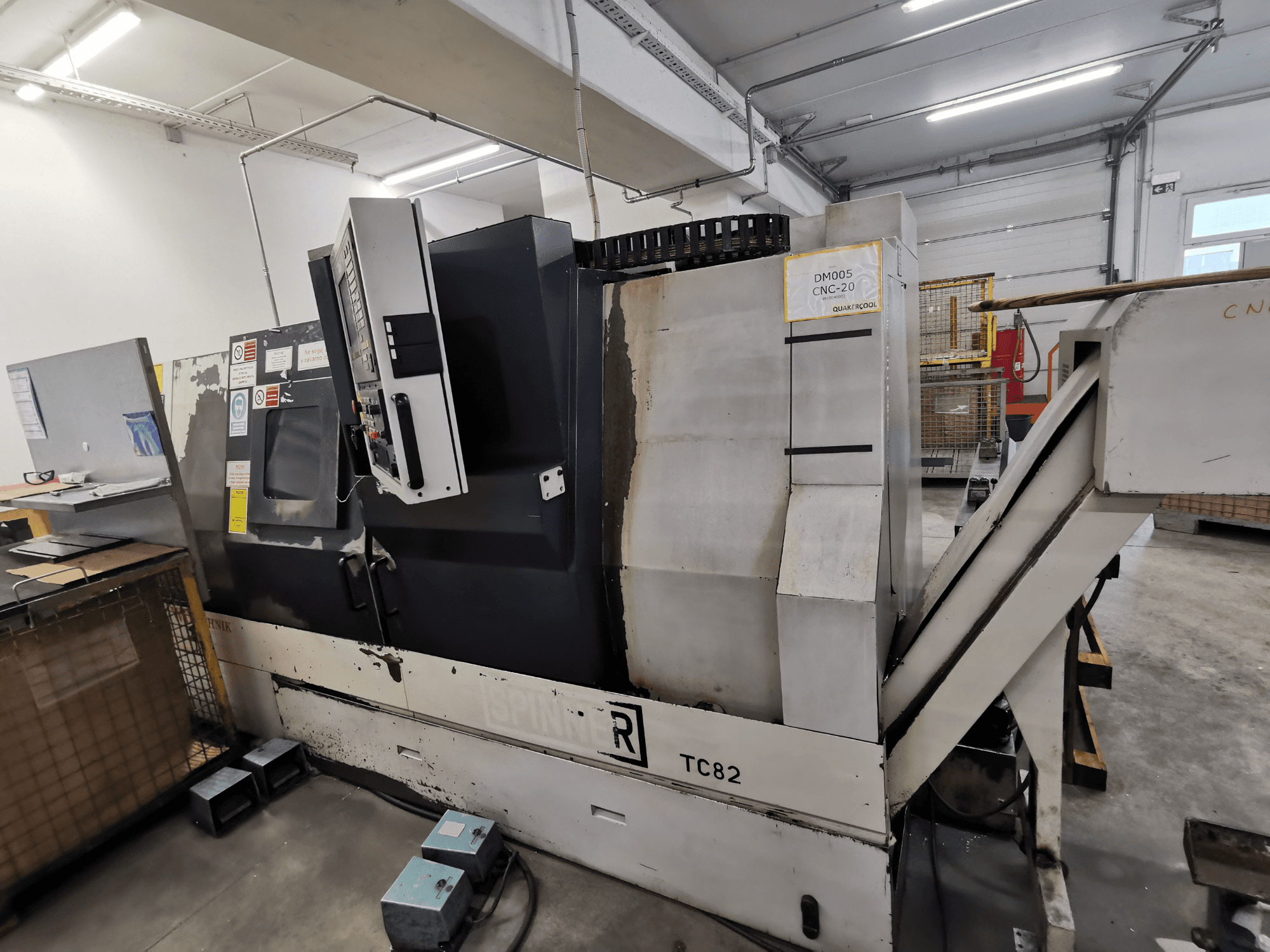 CNC-tööpink, kaubamärk Spinner, mudel TC82, külgvaade, millel on näidatud juhtpaneel ja jäägi eemaldamise šaht töökojas.