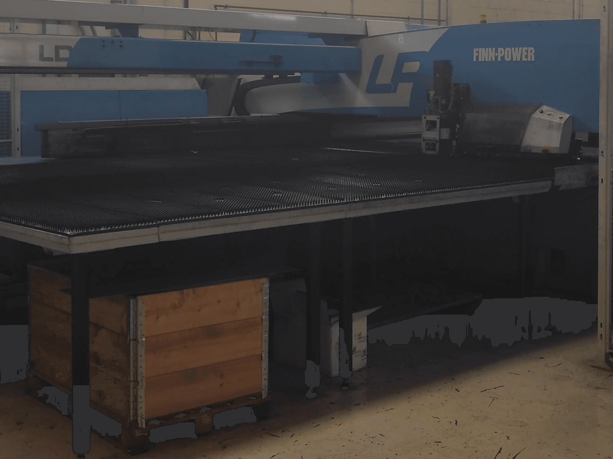 Finn-Power LP lõikemasin tehases, esivaade, mille all on tekstureeritud metalllaud ja puukast.