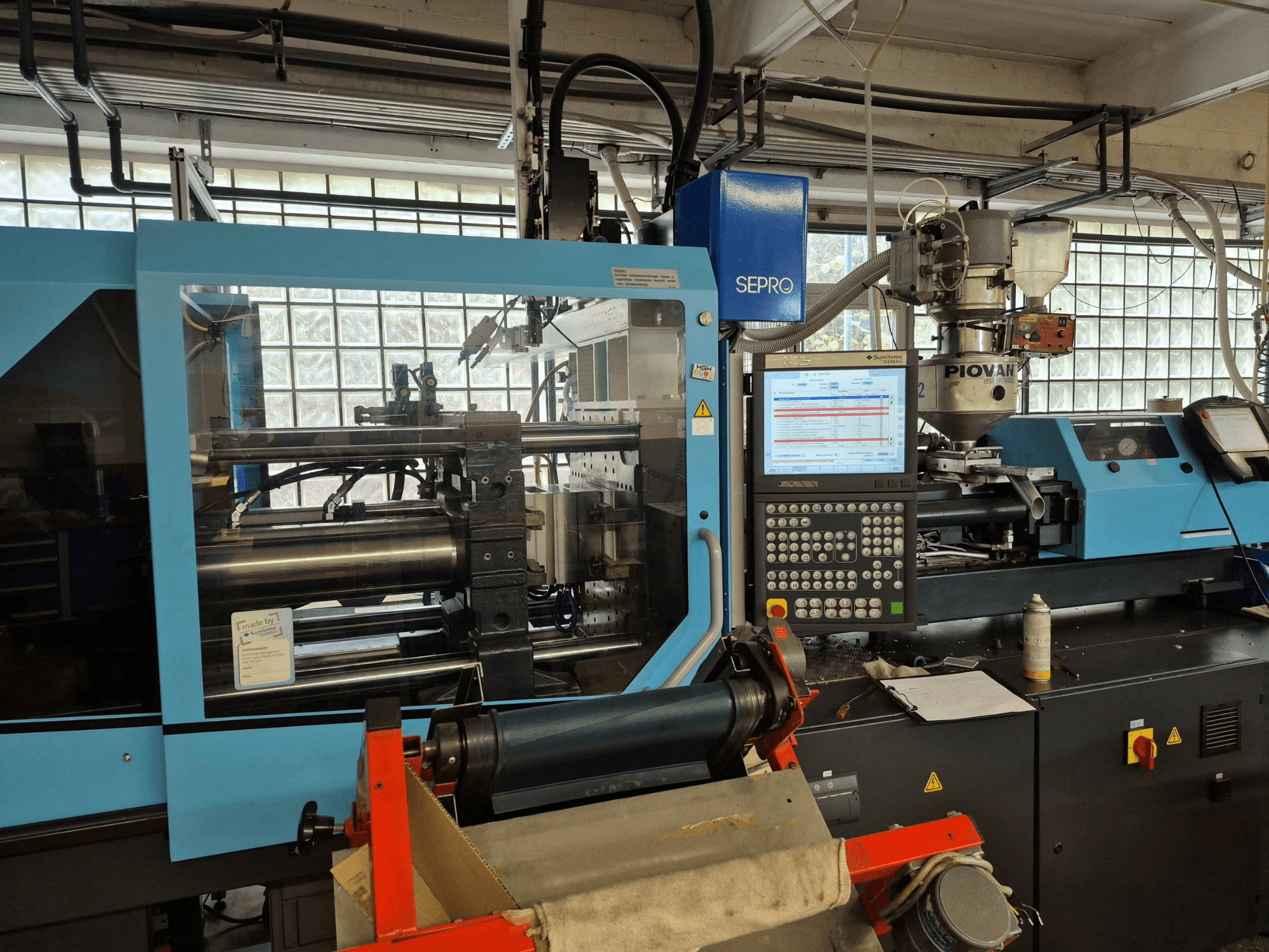 Hüdrauliline survevalumasin SUMITOMO SHI DEMAG Systec 120/470-430, vaade eest, kus on näha juhtpaneel ja materjalitoitesüsteem.