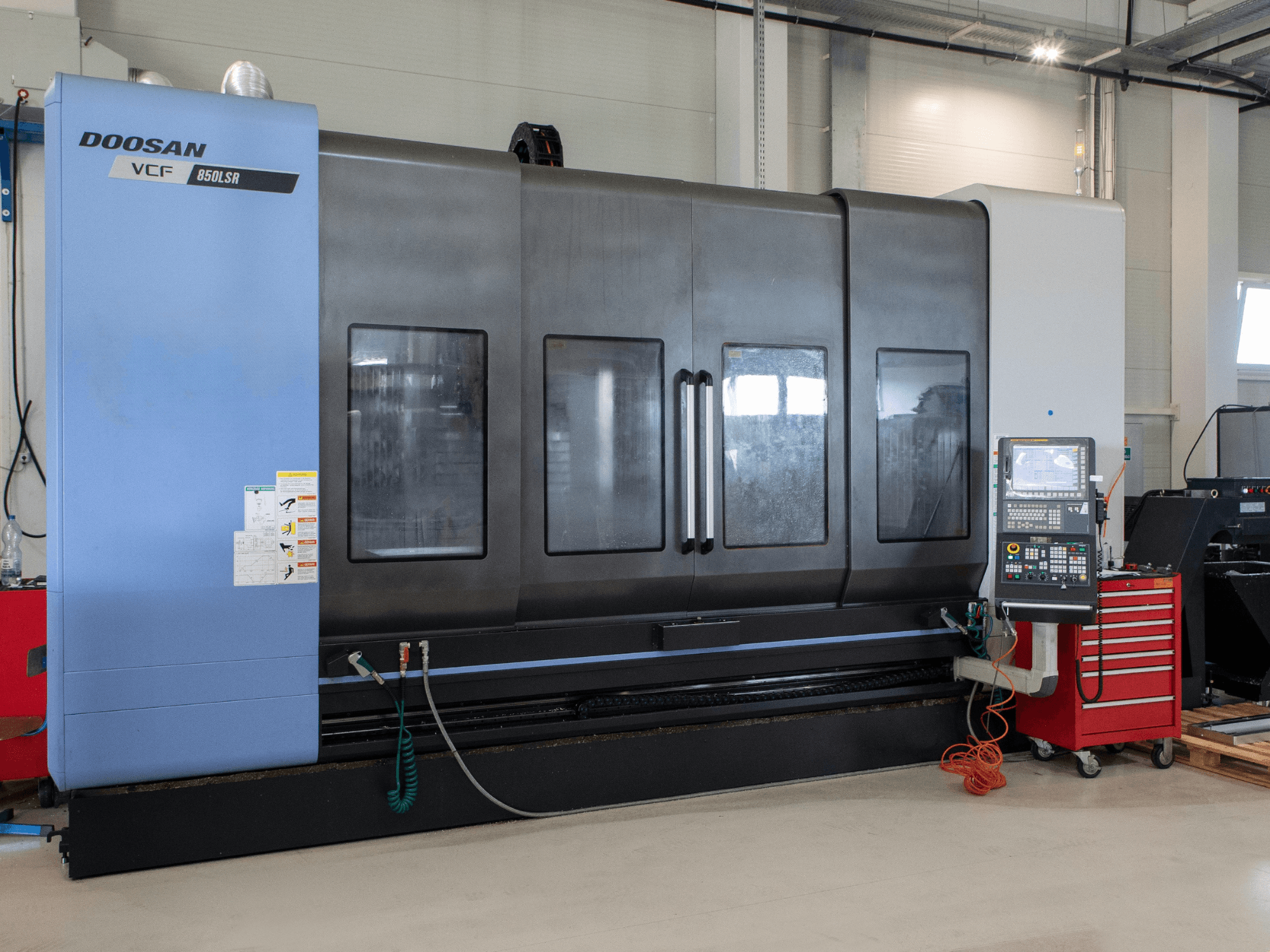 DOOSAN VCF850 frees- ja treimiskeskus, vaade eest; varustatud suurte kahepoolsete akendega, juhtpaneeliga ja tööriistade hoiukohaga. Ideaalne töötlemiseks.
