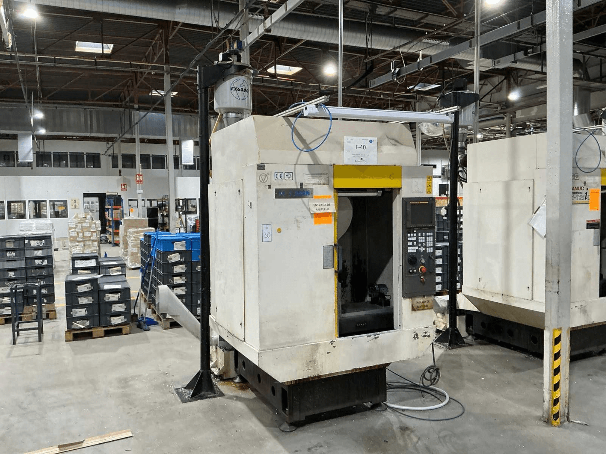 FANUC ROBODRILL α-T21iD, vertikaalse töötluskeskuse esiplaan tööstuslikus keskkonnas, juhtpaneeli detailid nähtavad.